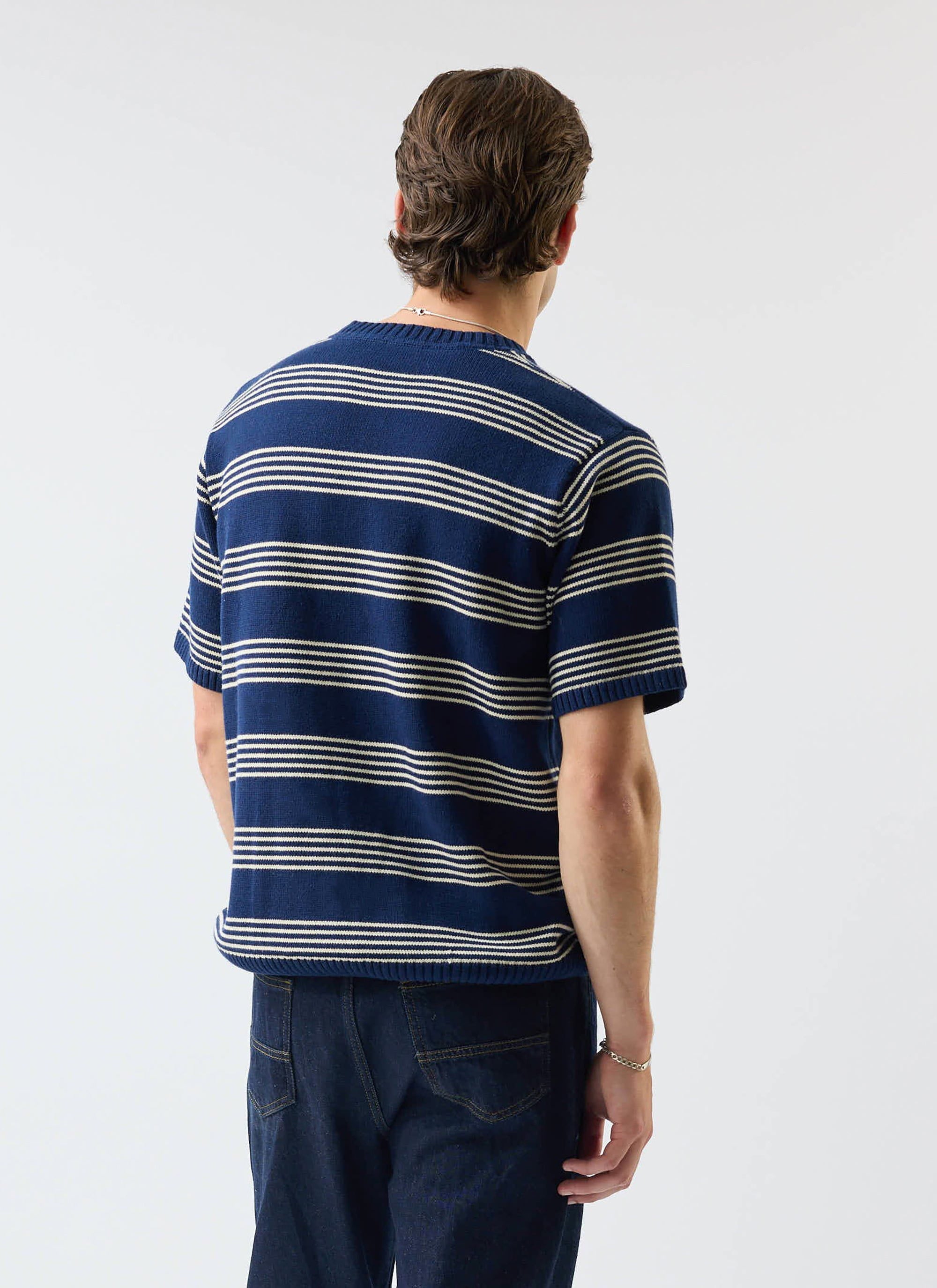 The back of the Percival Fiction Striped Knitted T Shirt in navy, as worn by a model with dark denim jeans.