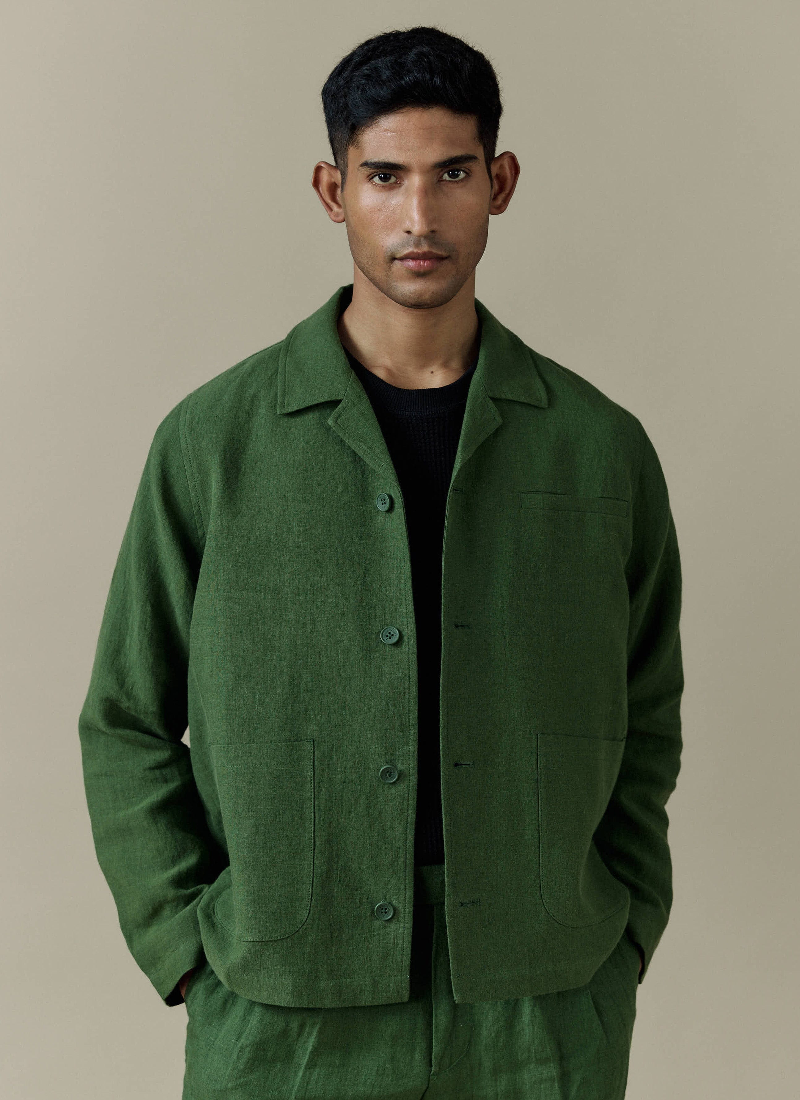 A model wears the Percival Linen Overshirt in Forest, styled with matching trousers and a black t-shirt.