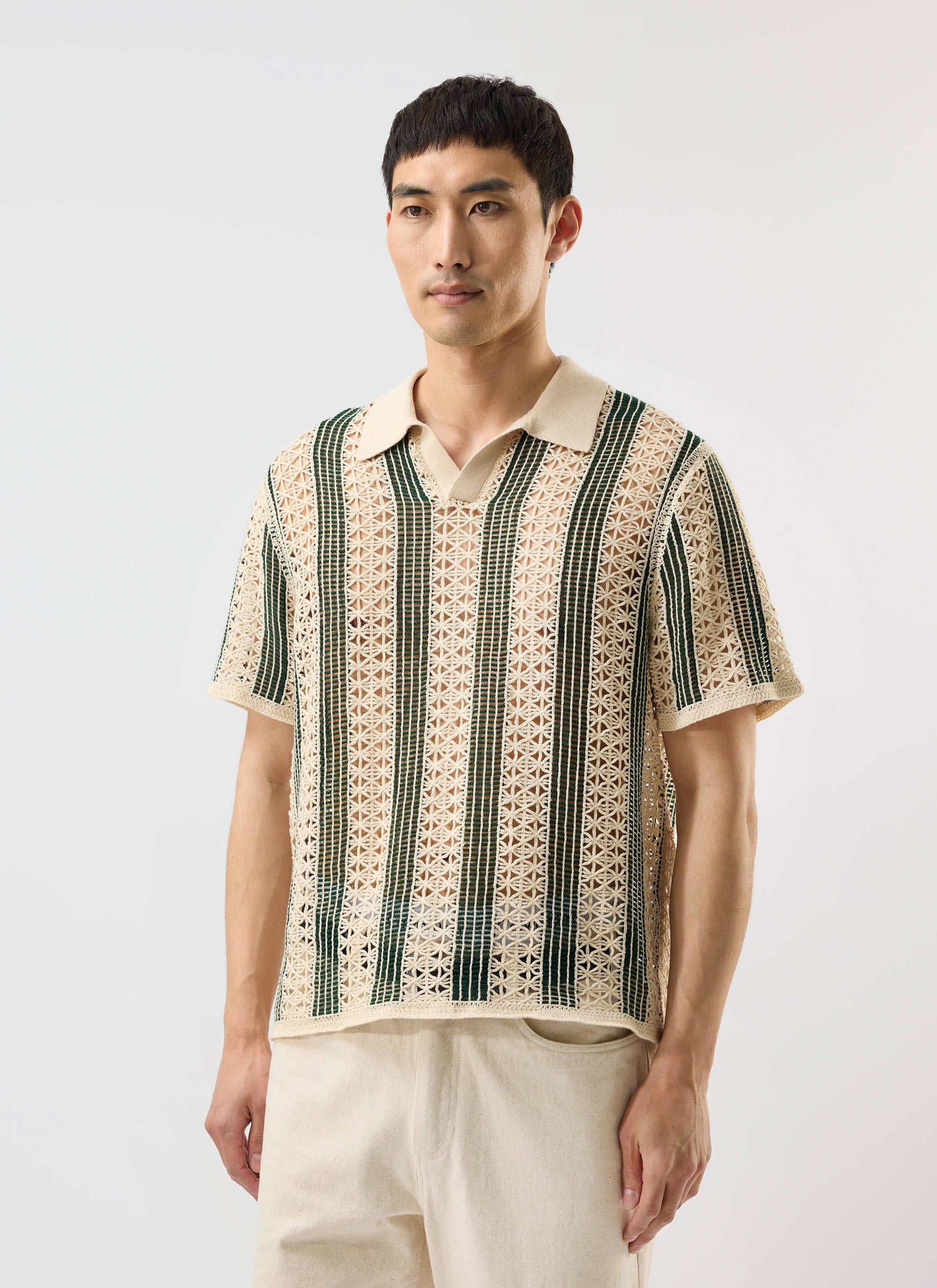 A model wears the Percival Sarti crochet knitted polo shirt in ecru with forest green stripes against a plain background.