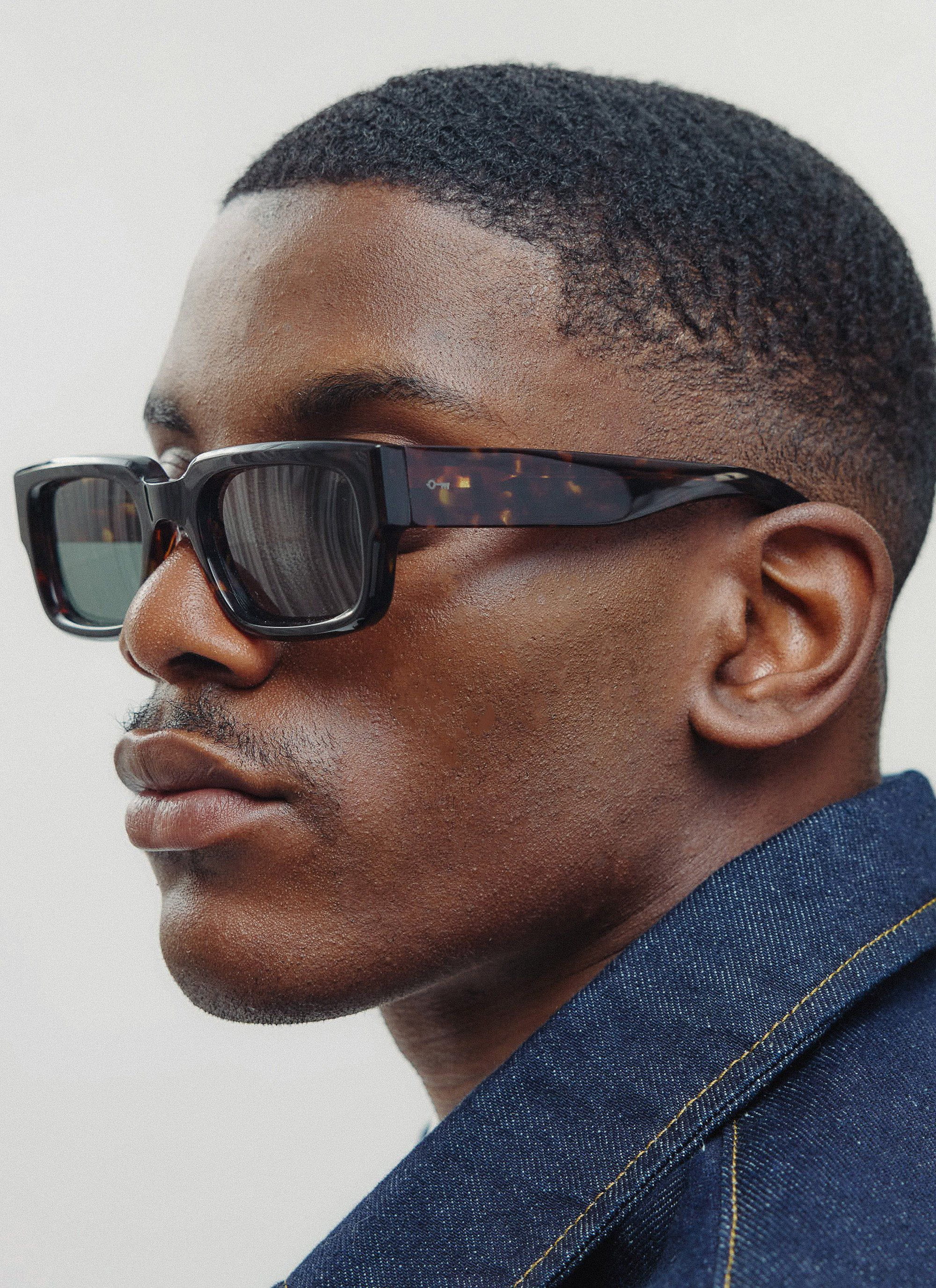 A close-up profile of a model wearing the Percival Demi Brown Tortoise sunglasses with bottle green lenses.