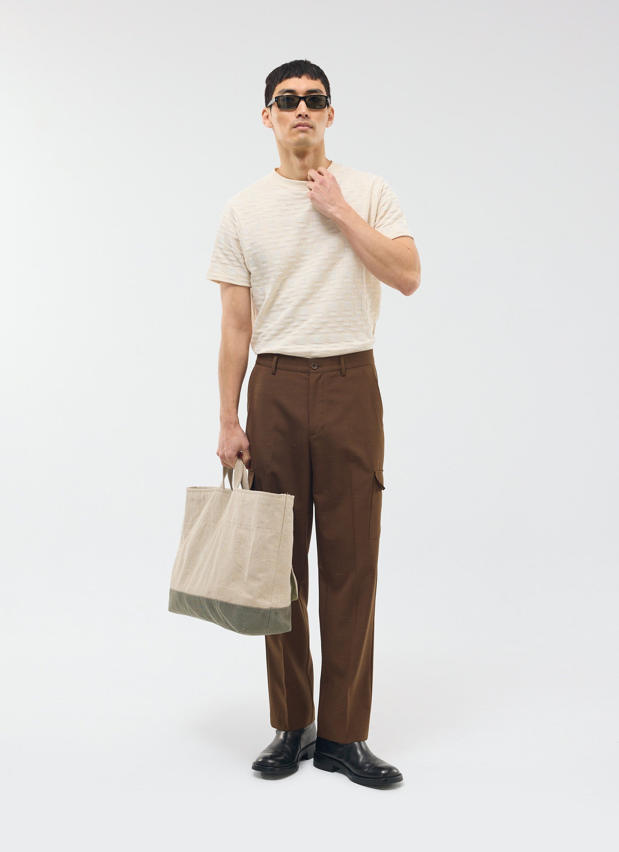 The Percival Trentino Tailored Patch Pocket Trouser in brown, styled on a model with a t-shirt, tote bag and sunglasses.