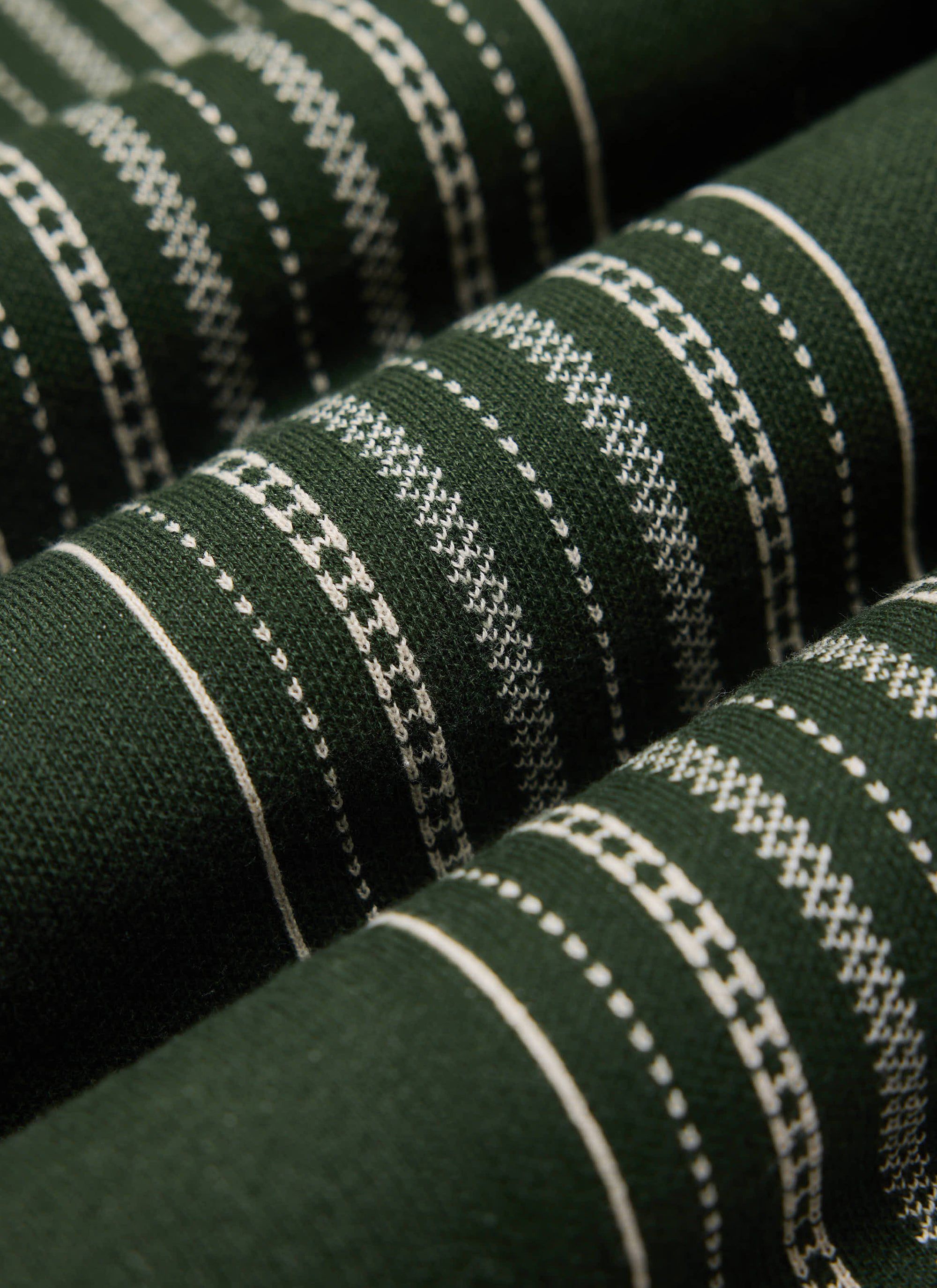 A close-up of the Percival Accolades Knitted Shirt in forest green, showing the detailed book spine jacquard cotton knit.