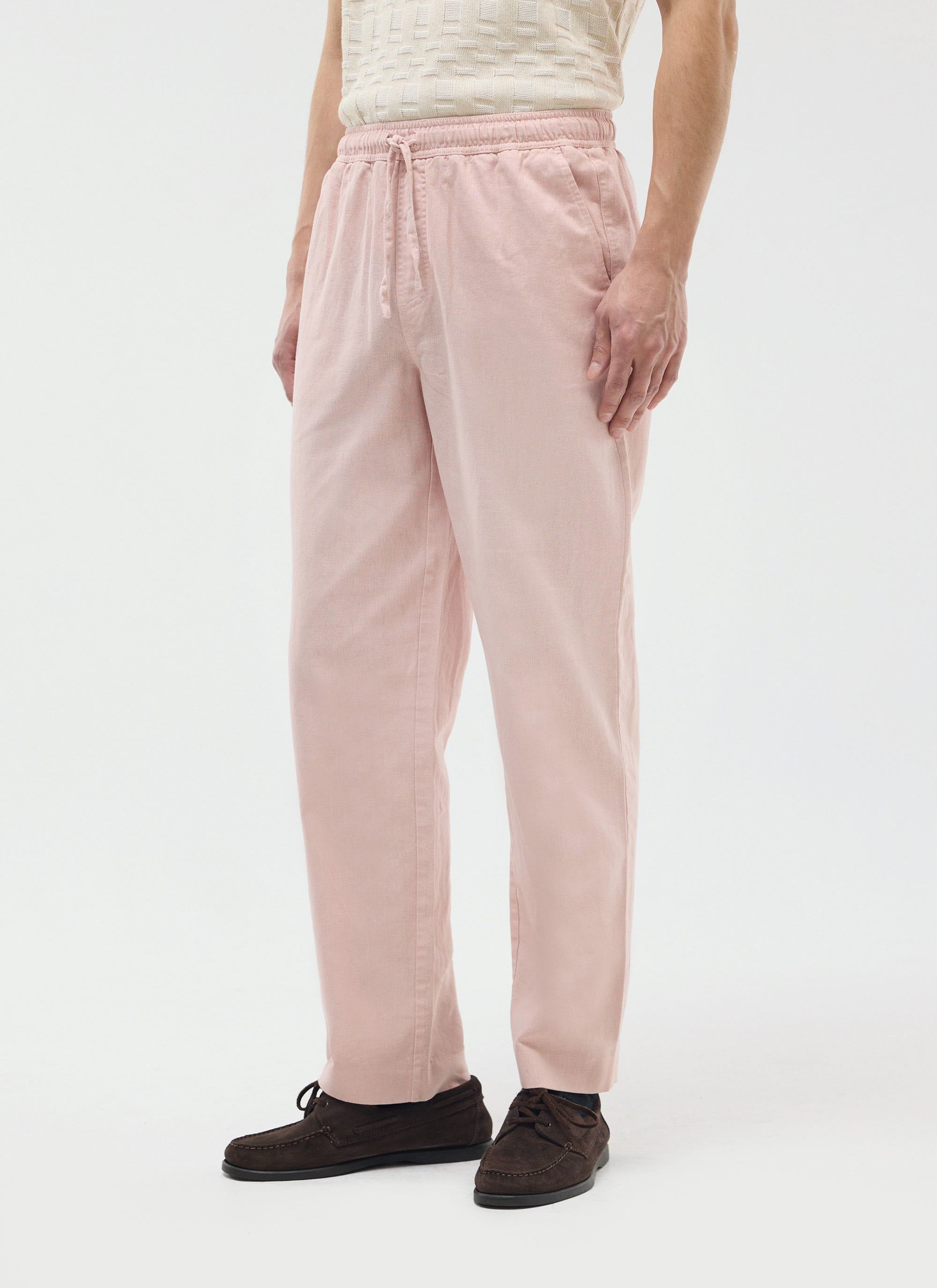 A model wears the Percival Linen Everyday Trousers in dusty pink, styled with a textured knit top and dark suede shoes.