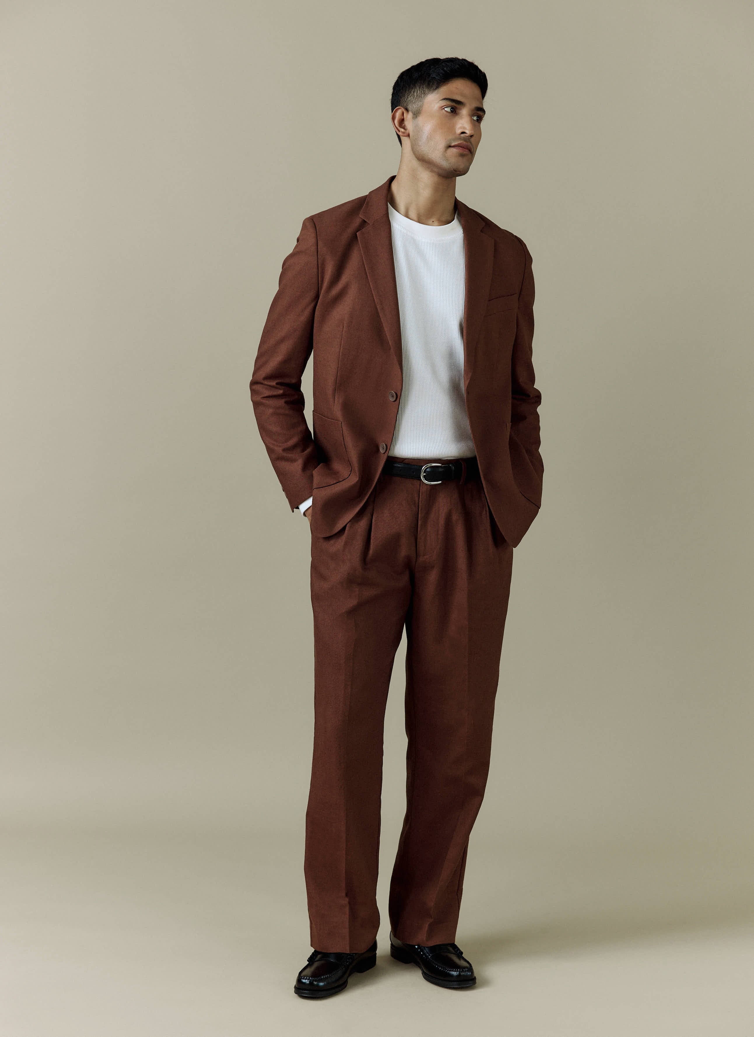 A model wears the Percival Tailored Linen Blazer and matching trousers in brown, styled with a white t-shirt.