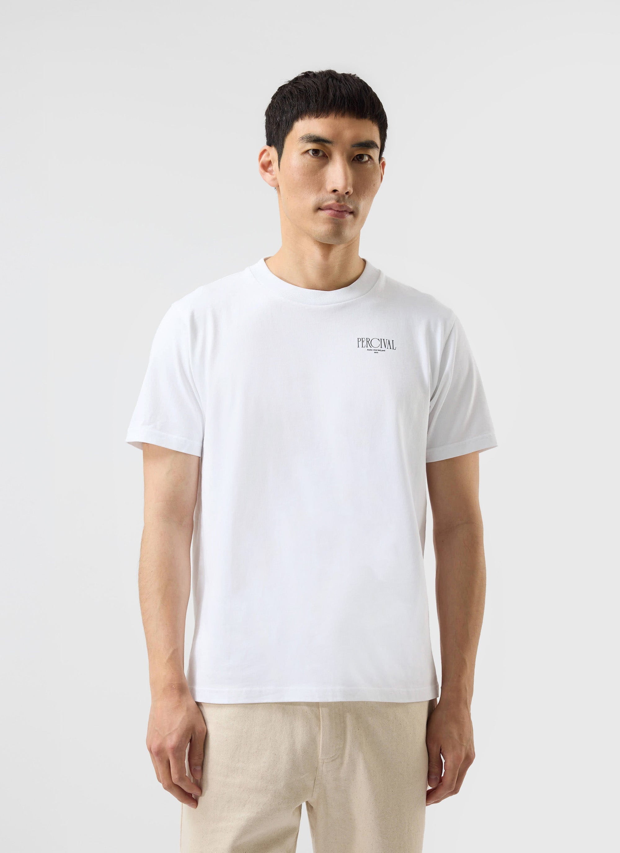 A model wears the Percival Bistro T-Shirt in white organic cotton, featuring a small embroidered logo on the chest.