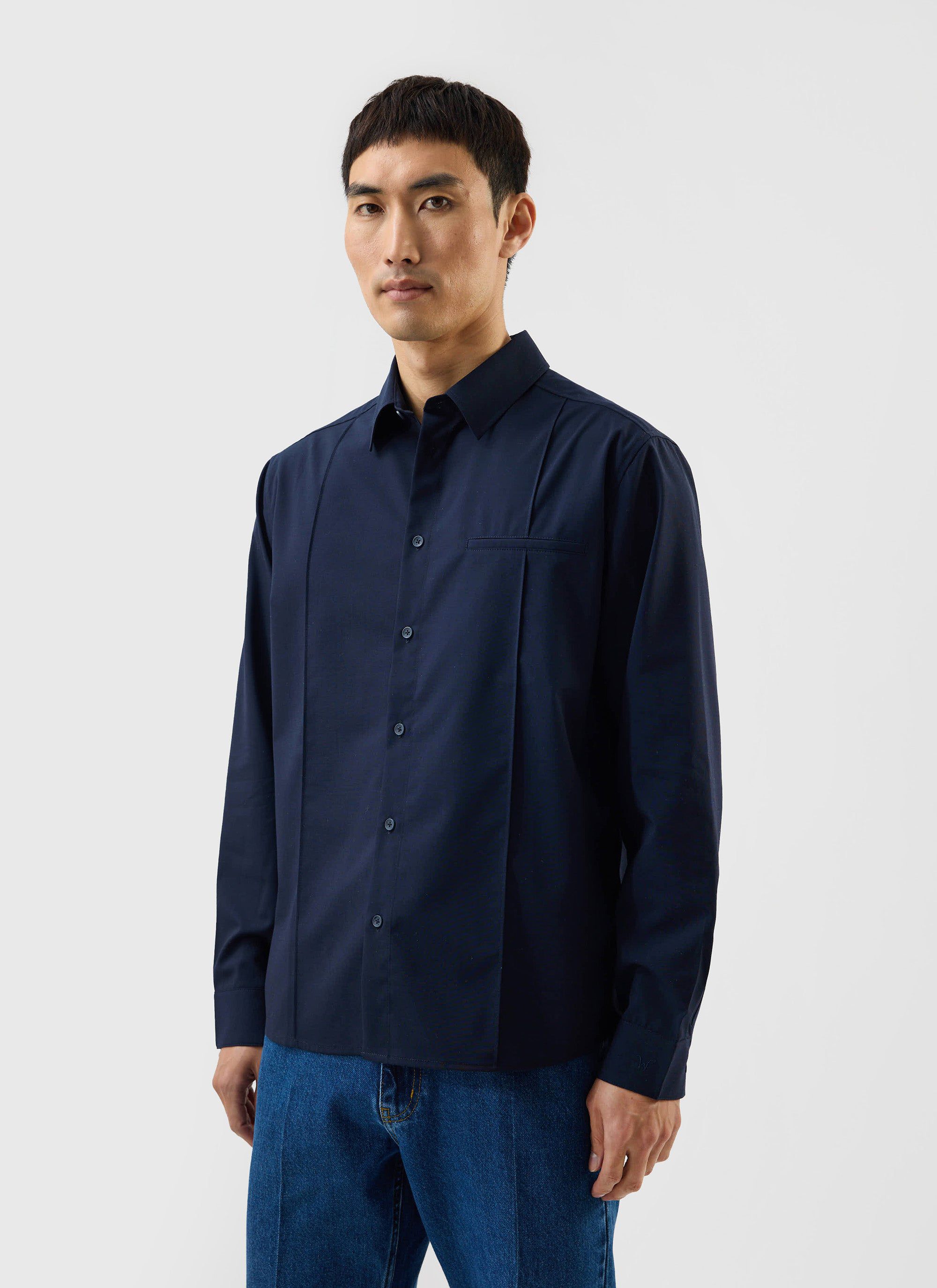 A model wears the navy blue Percival x Warren Pleated Shirt, showing its oversized fit and pleated front details.
