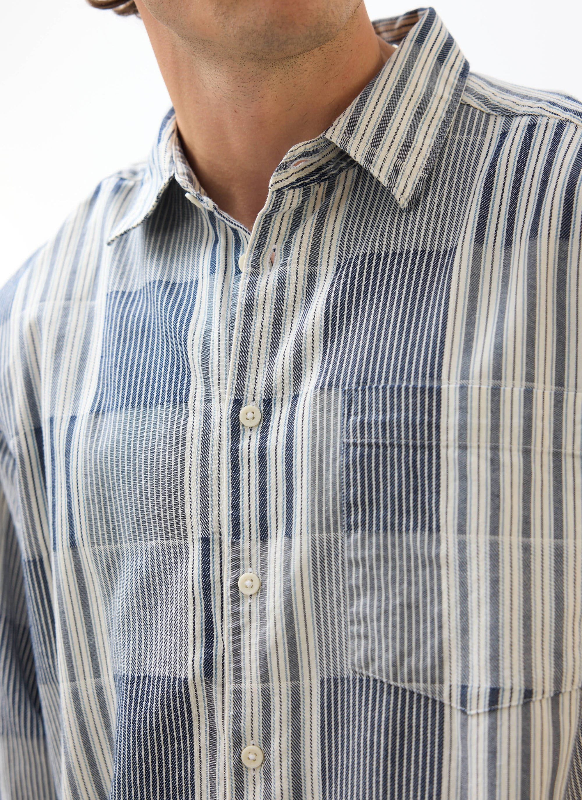 Close-up of a model wearing the blue Percival Epigraph Patchwork shirt, showing the striped cotton jacquard and chest pocket.