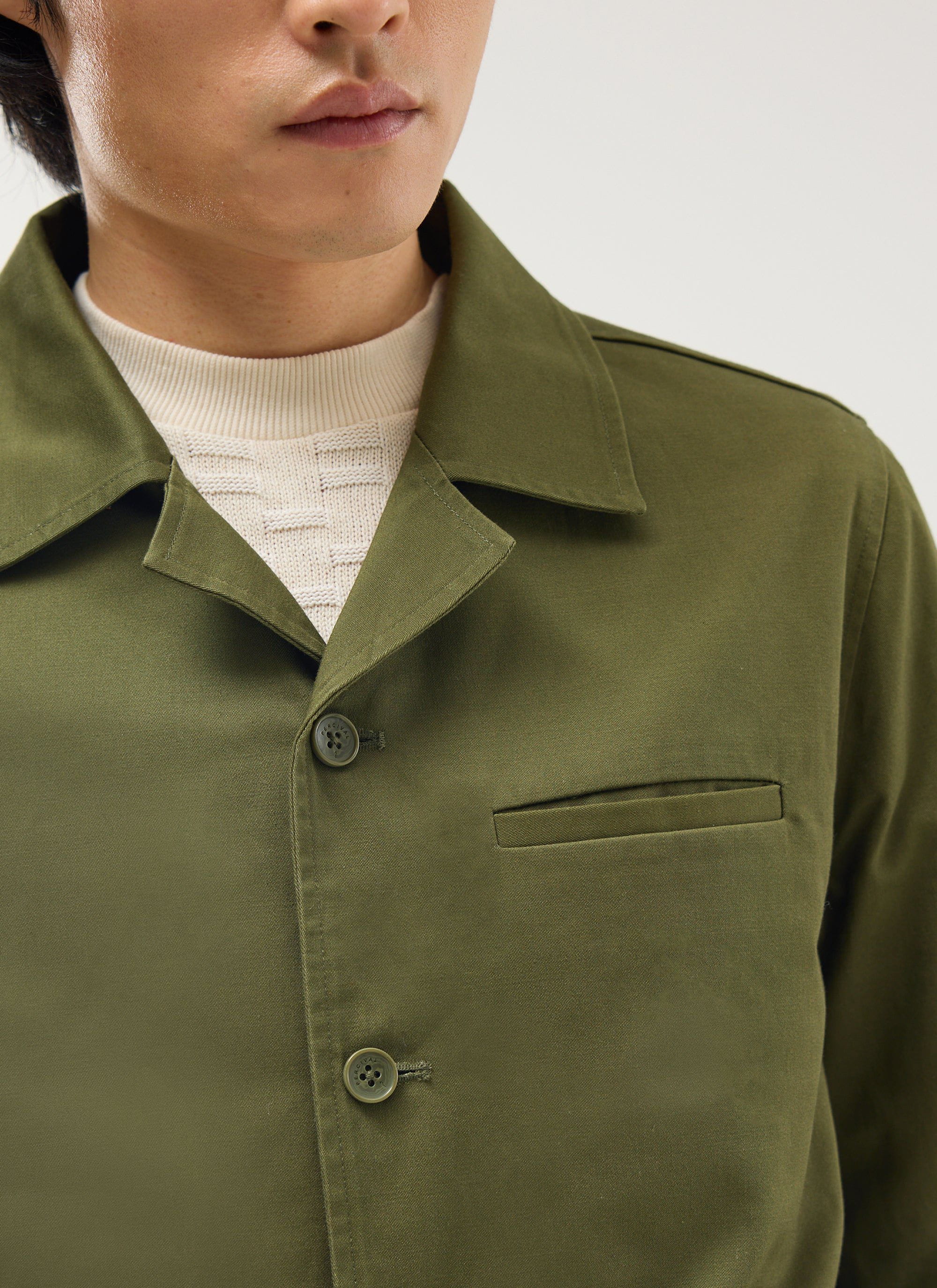Close-up of a model wearing the Percival Casual Workwear Jacket in khaki cotton, showing the collar and jetted pocket detail.