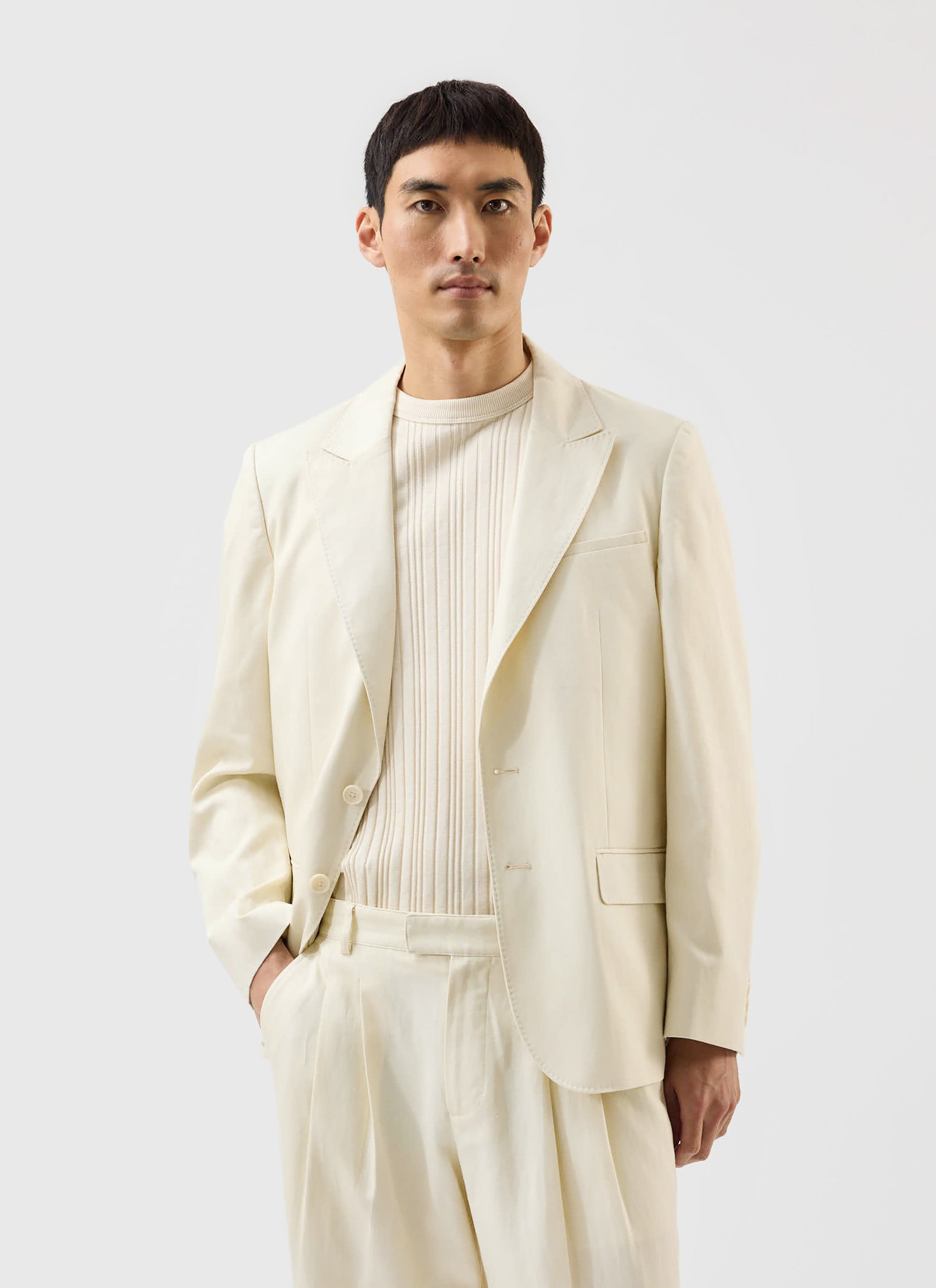 A man models the Percival x Warren Lyocell Tailored Blazer in ecru, paired with matching trousers and a ribbed knit top.