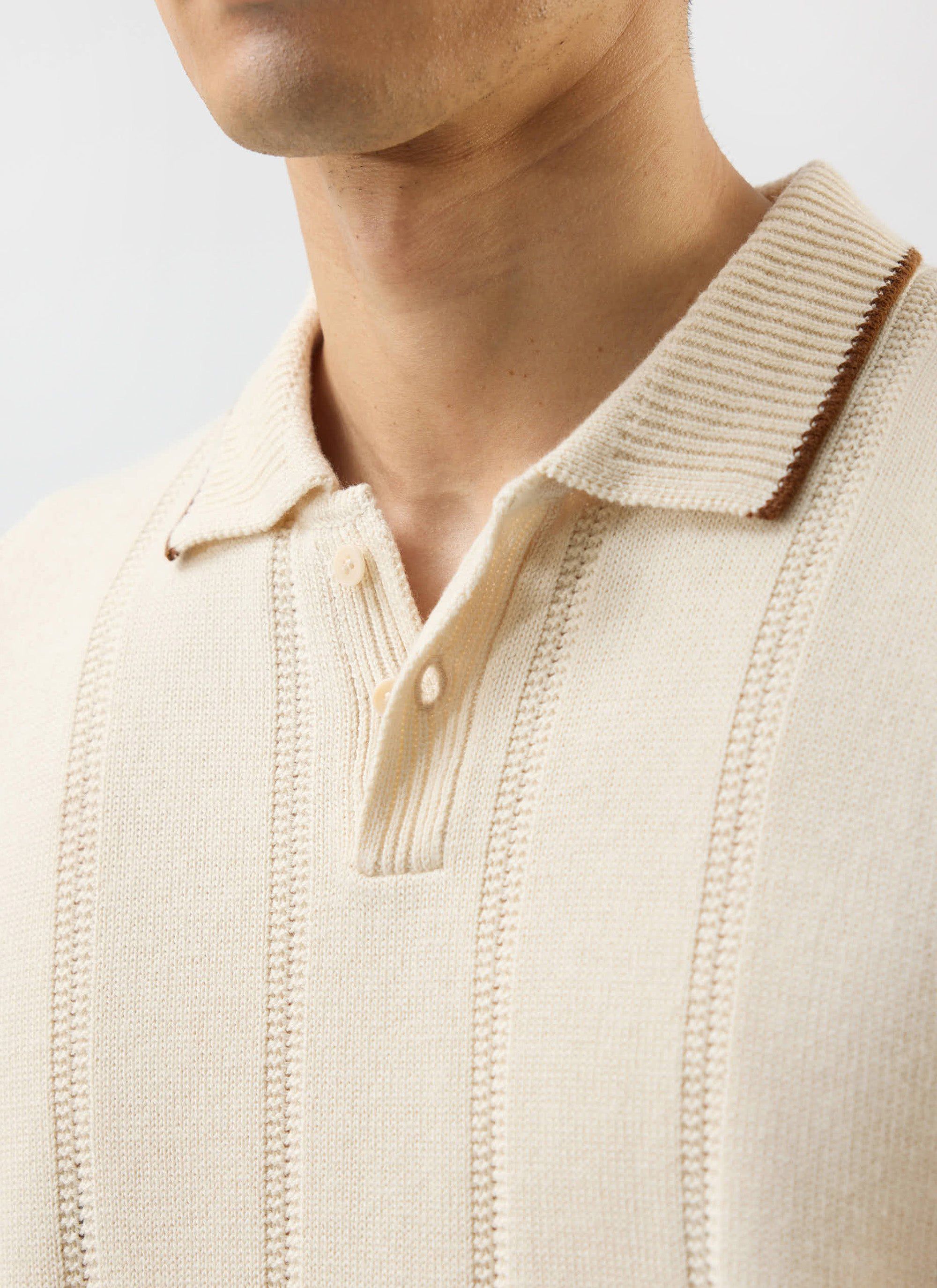 A close-up of the Percival x Warren knitted polo in ecru, detailing the vertical texture and contrast tipping on the collar.