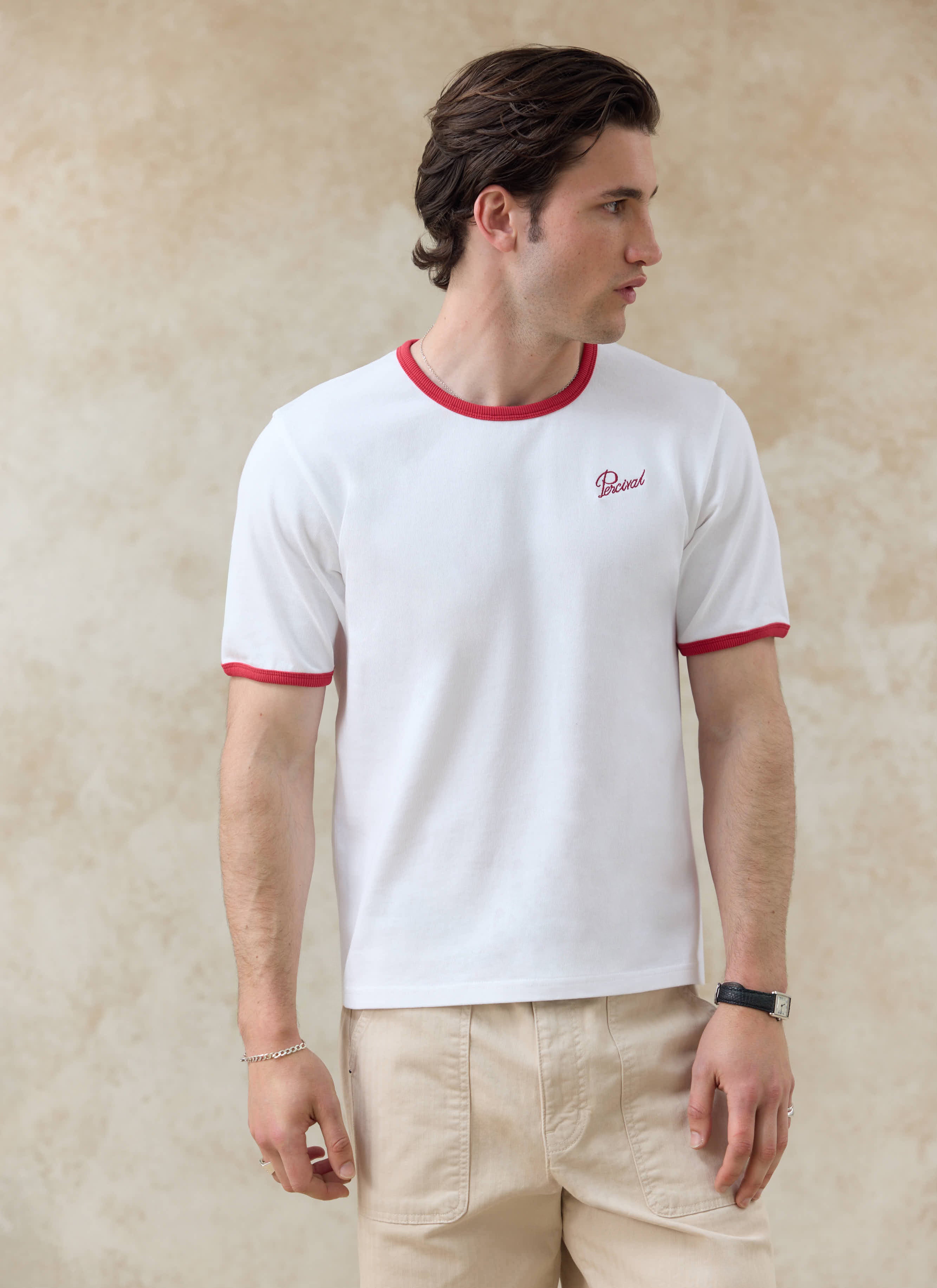 Percival white organic cotton ringer t-shirt with red trim, part of the SS26 collection styled with beige trousers.