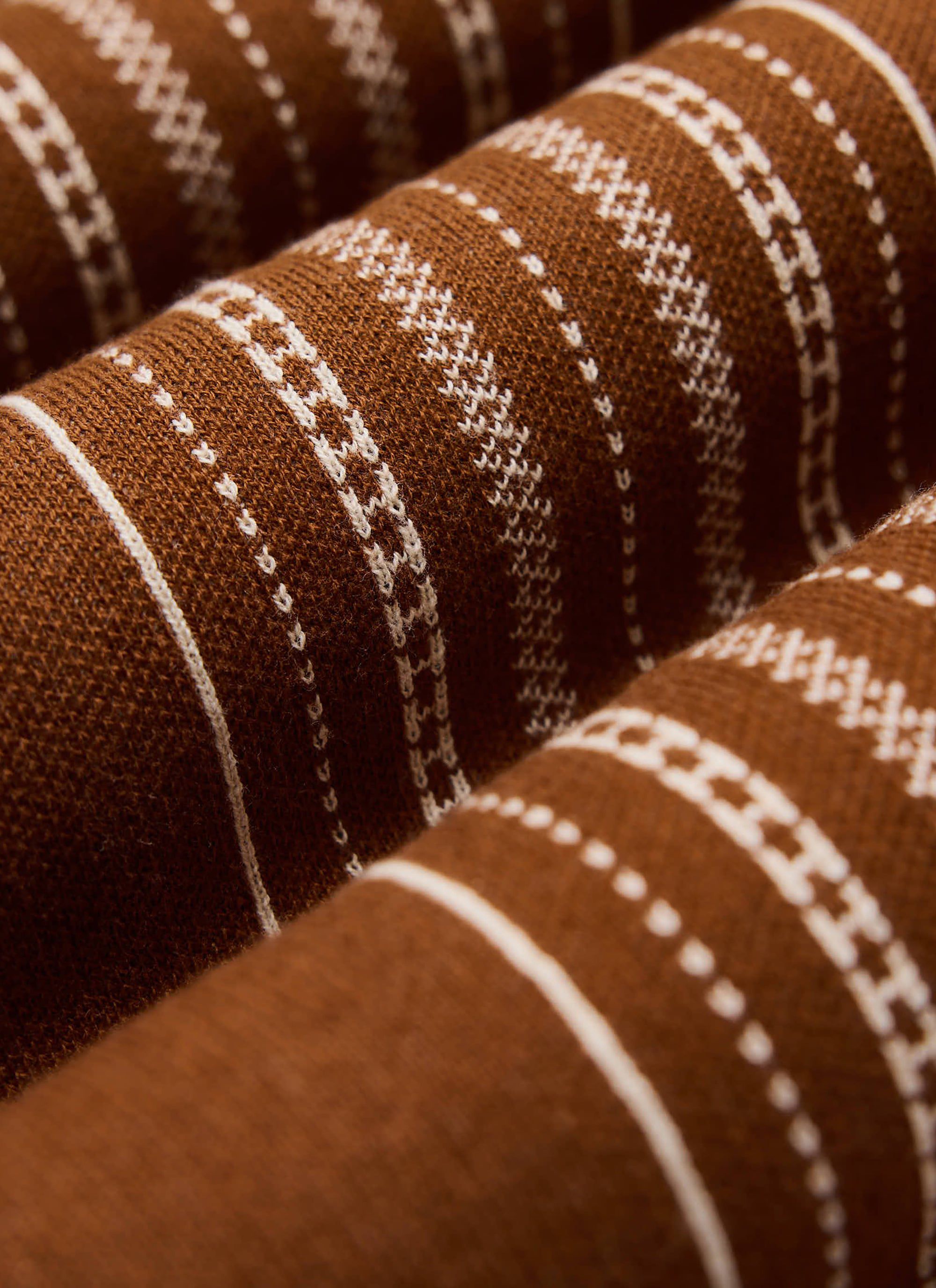 A close-up of the intricate book spine jacquard pattern on the tobacco brown Accolades Knitted Shirt from Percival.
