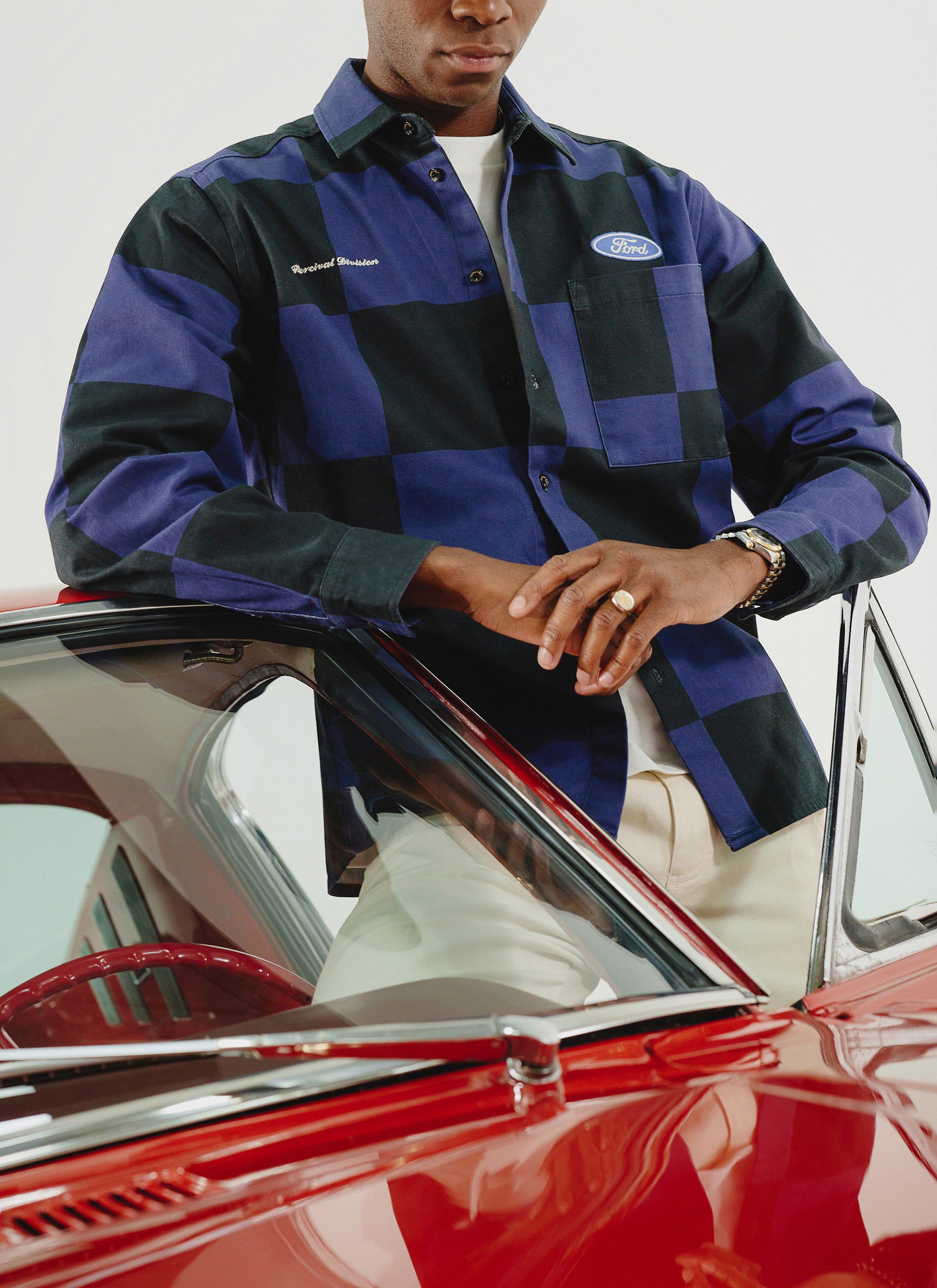 Percival x Ford navy and black checkerboard overshirt worn by a model leaning on a vintage red car.