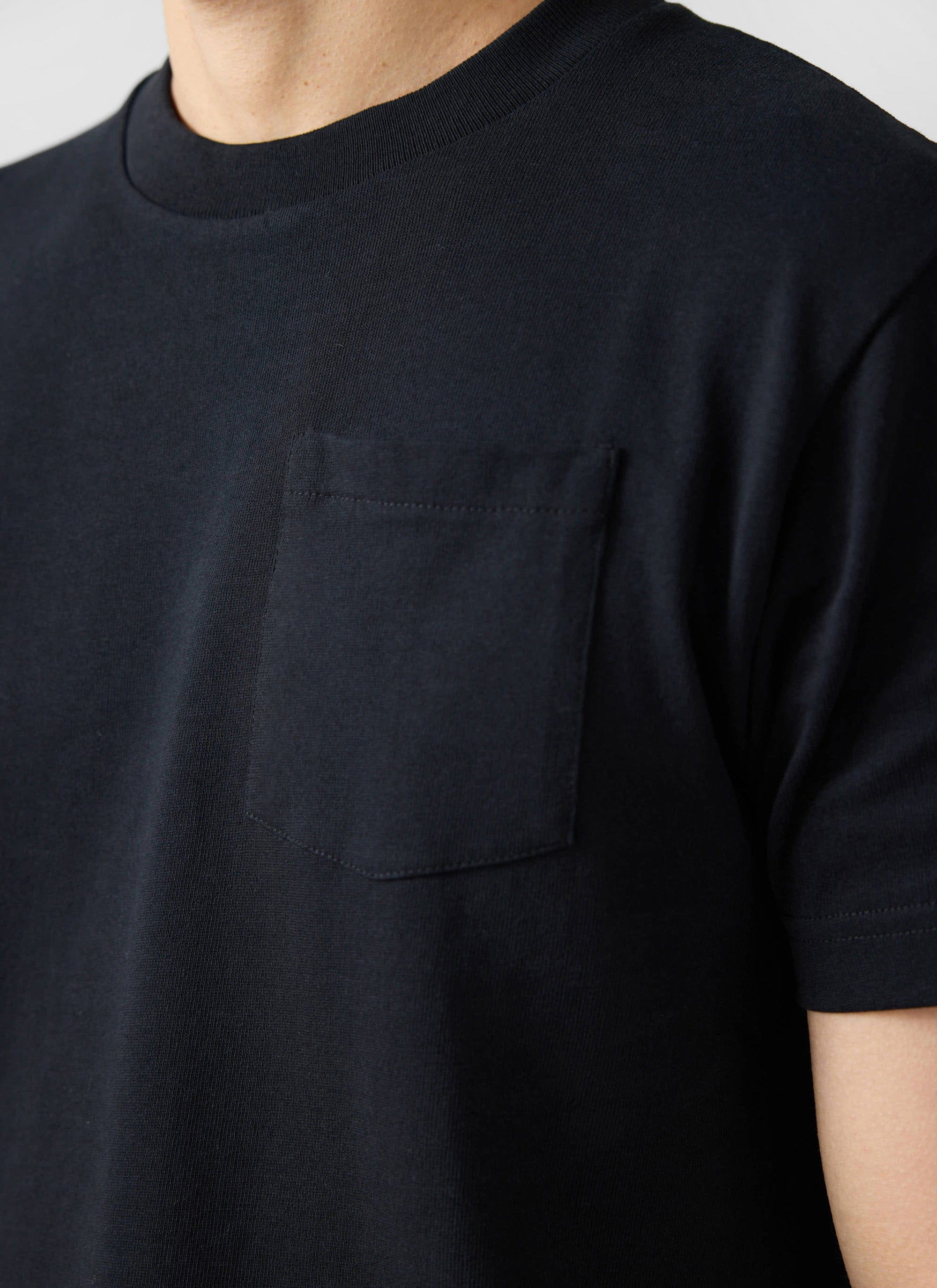 Close-up of the Percival Short Sleeve Pocket T-Shirt in black organic cotton, showing the crew neck and chest pocket.