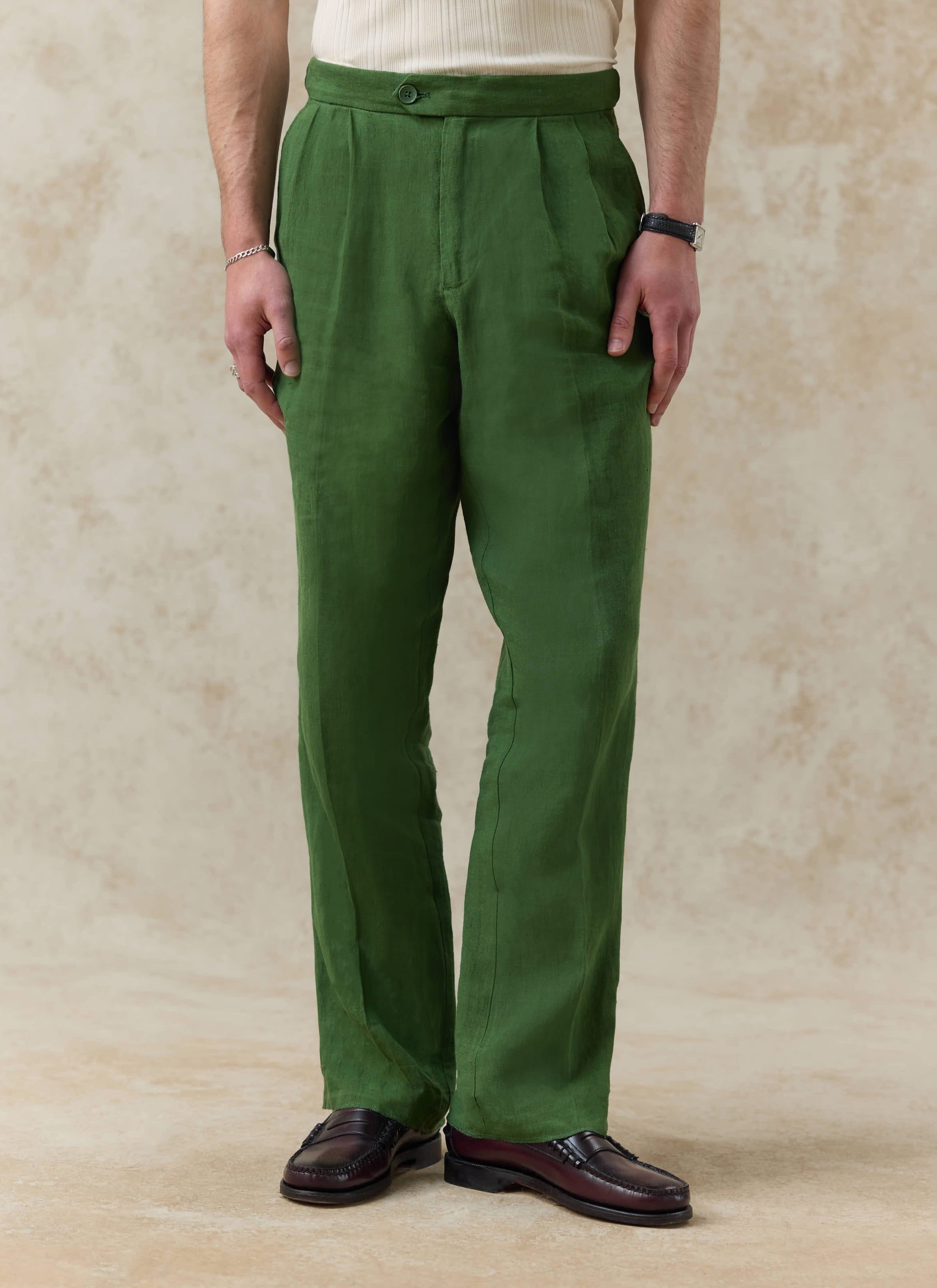 Relaxed fit Percival pleated tailored trousers in forest green linen, showing the textured fabric and button waist.