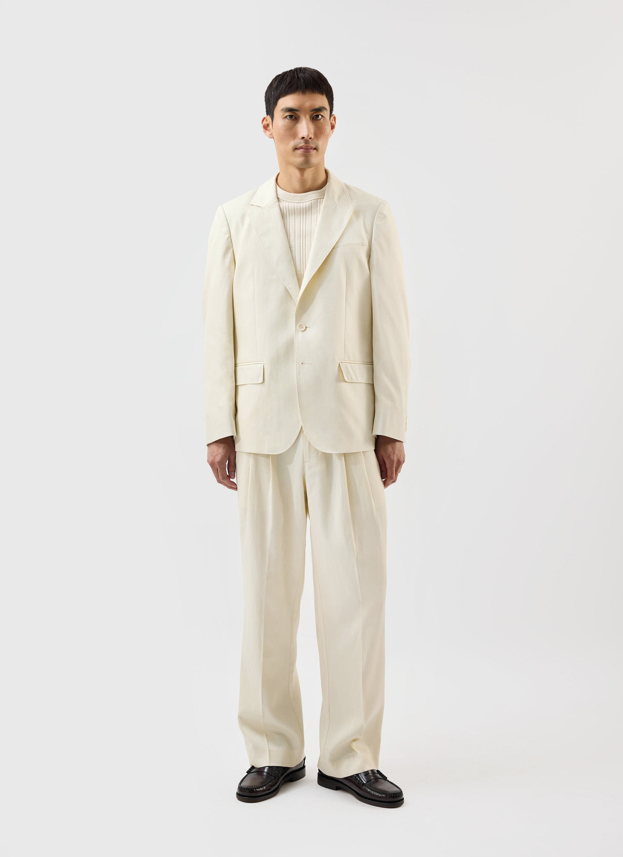 A model wears the full ecru Lyocell suit from the Percival x Warren collaboration against a white studio background.