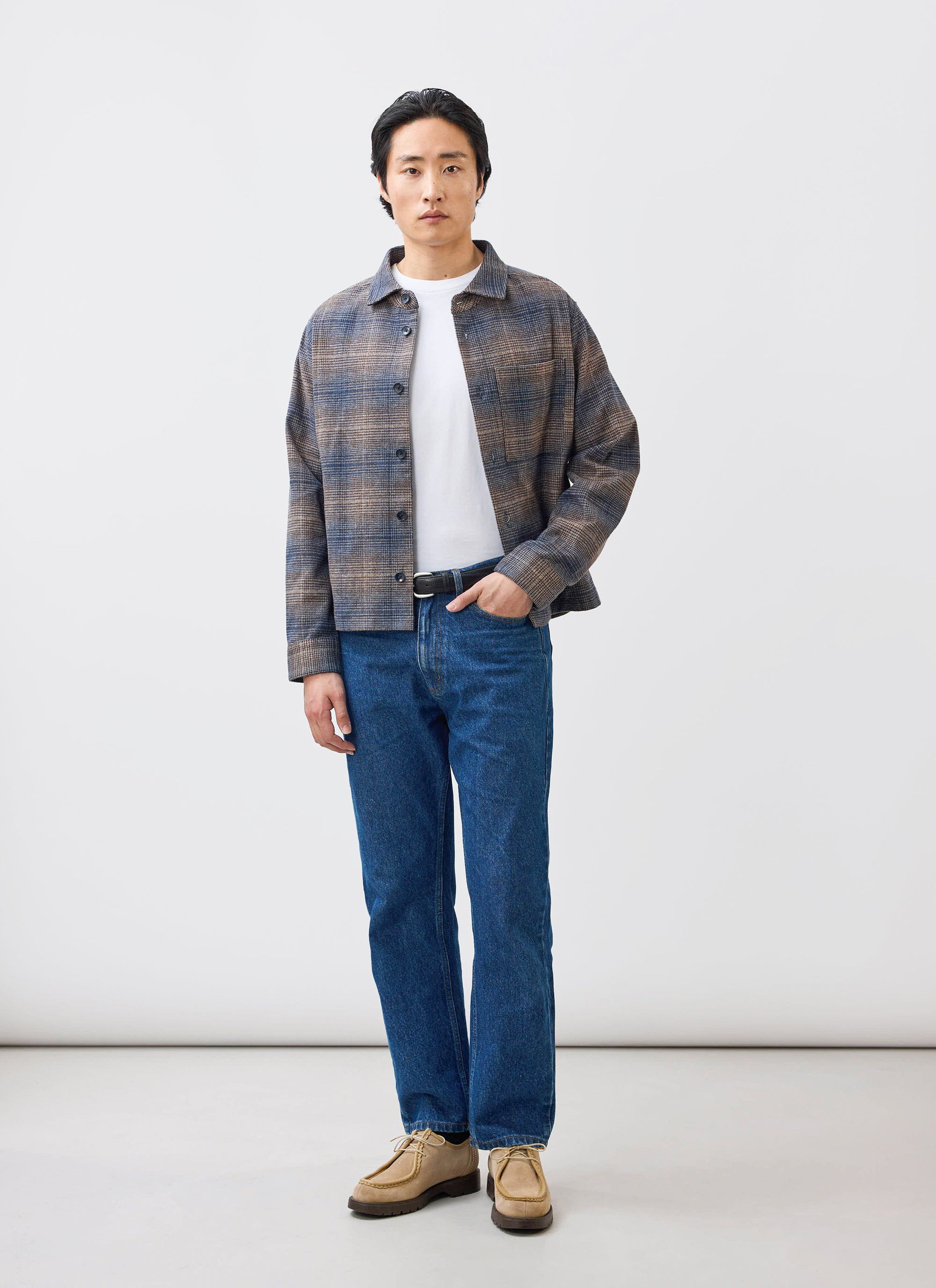 A model wears the Percival Luton Check Overshirt in brown over a white t-shirt and blue jeans against a white background.