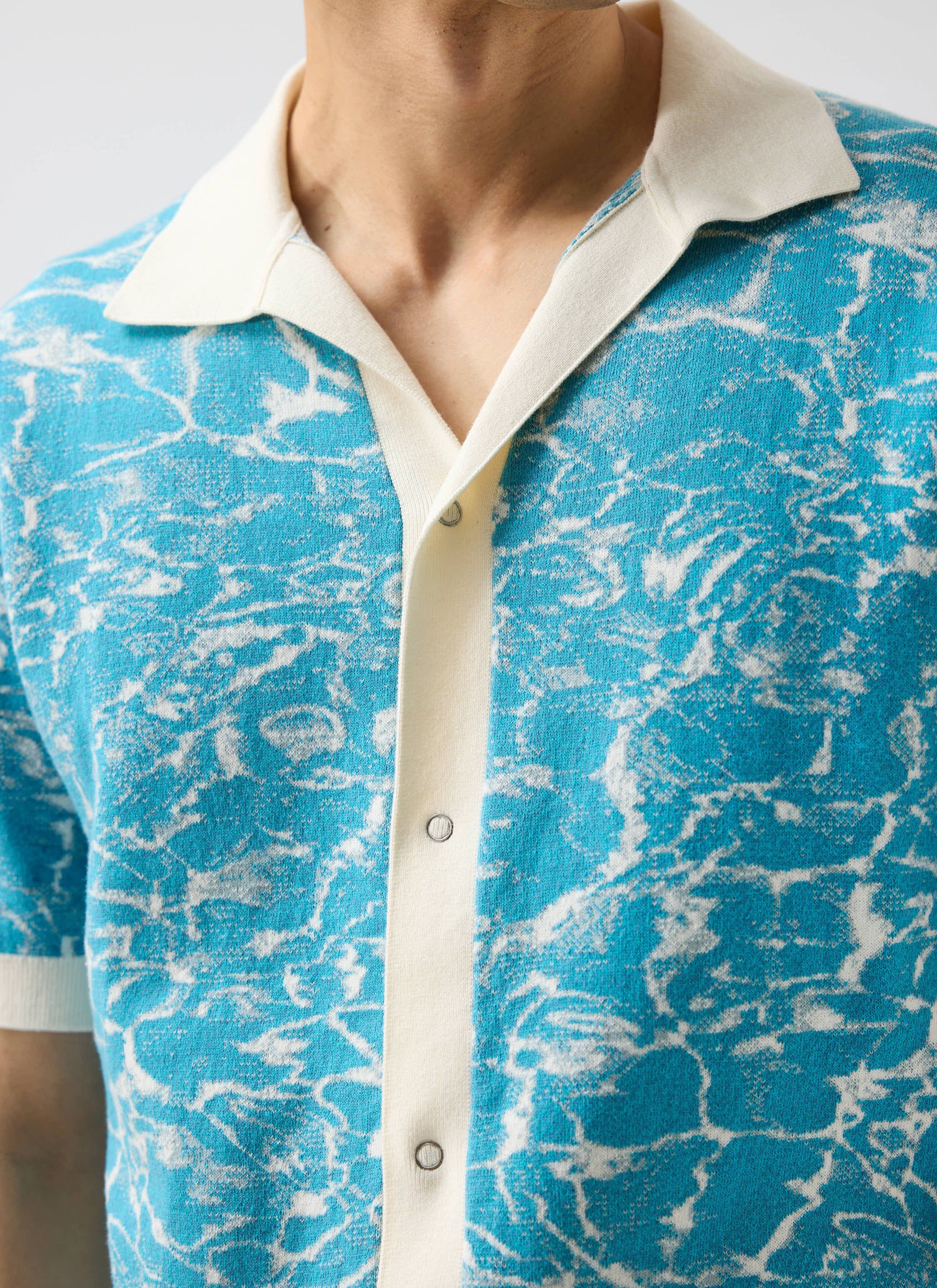 Close-up detail of a model wearing the blue and white ocean-patterned Farraris Negroni Knitted Shirt by Percival.
