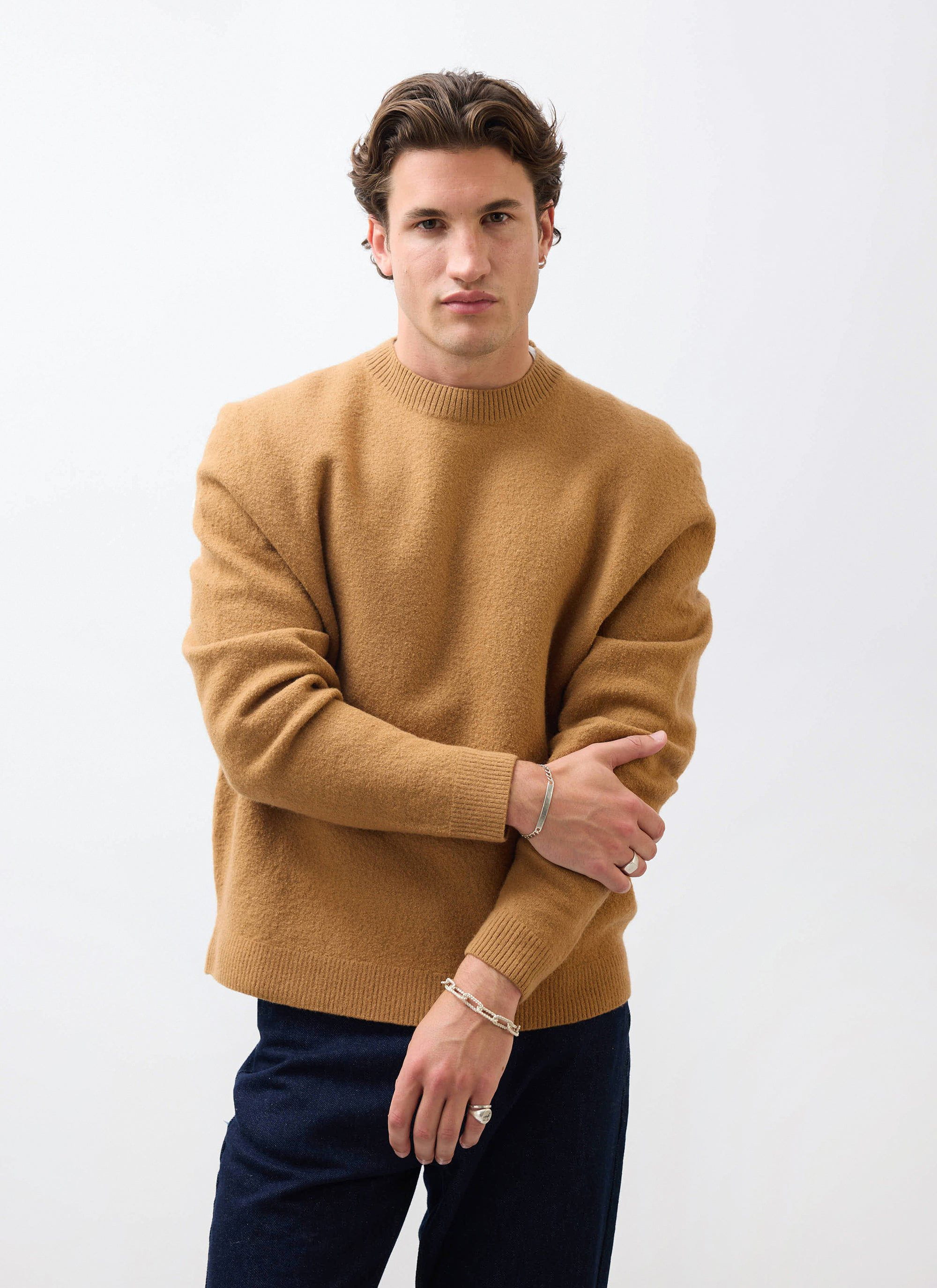 A model wears the Percival Felted Wool Jumper in brown, posing against a white studio background.