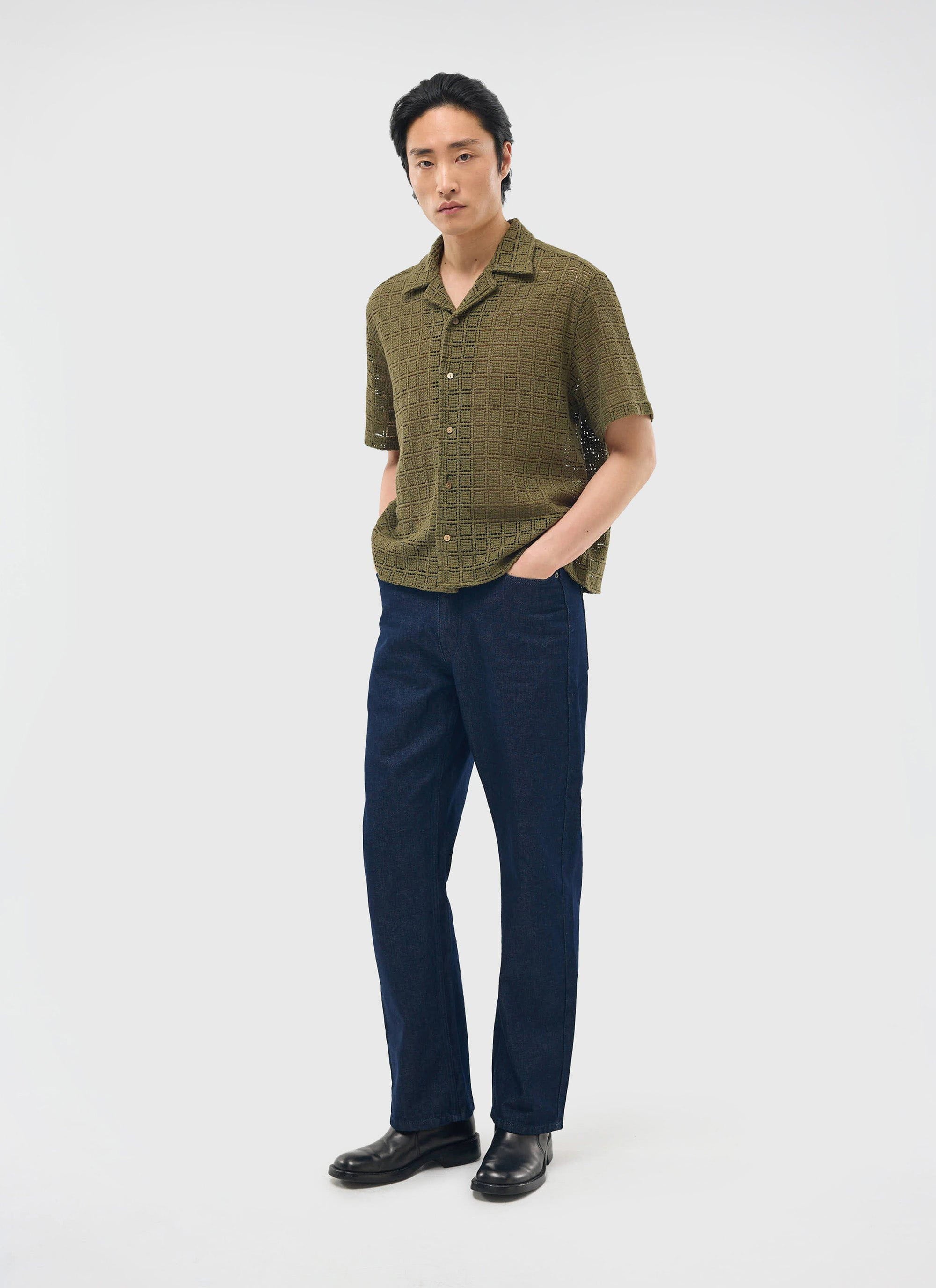 A model wears the olive green Palermo Crochet Cuban Shirt from Percival with dark blue jeans against a white background.