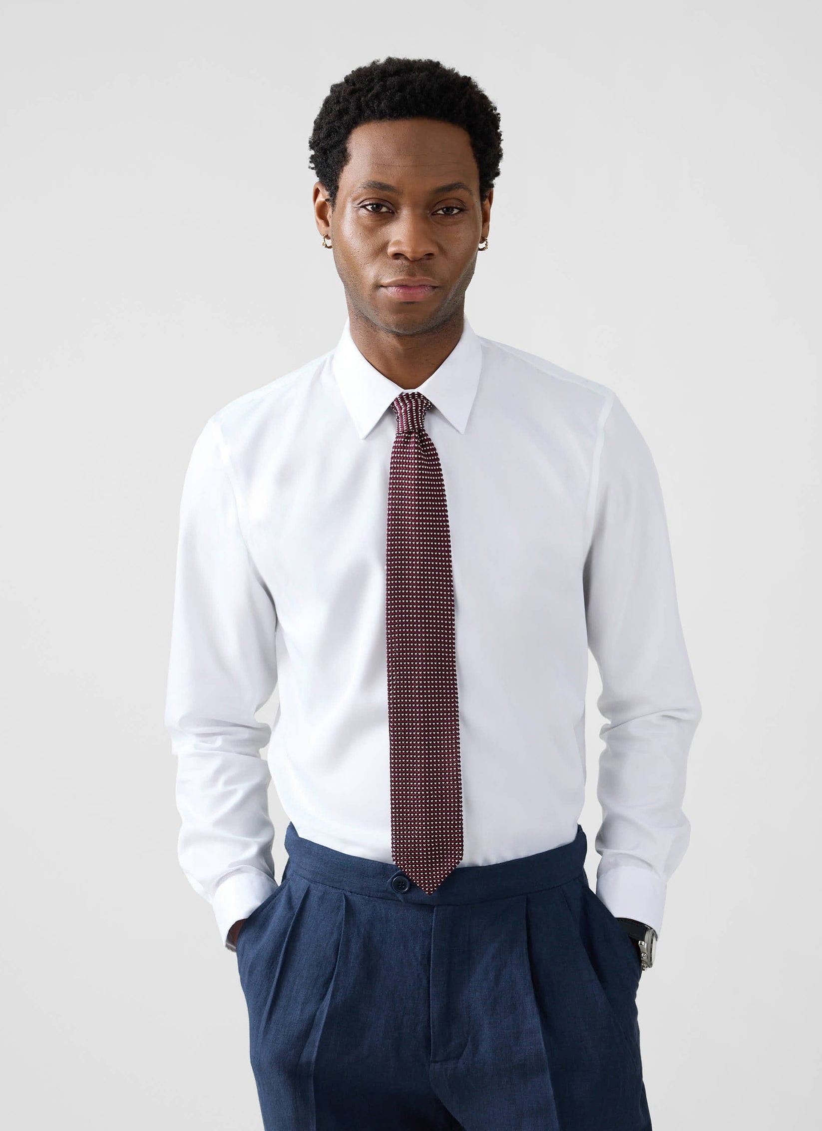 A model wears the Percival Formal Classic Shirt in white, styled with a patterned tie and navy pleated trousers.