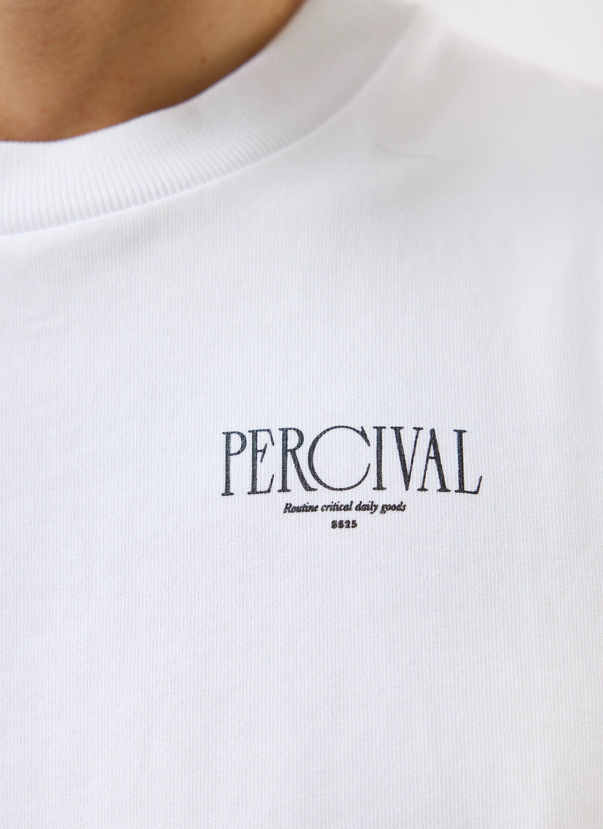 A close-up of the black embroidered Percival logo on the chest of the white Bistro T Shirt.