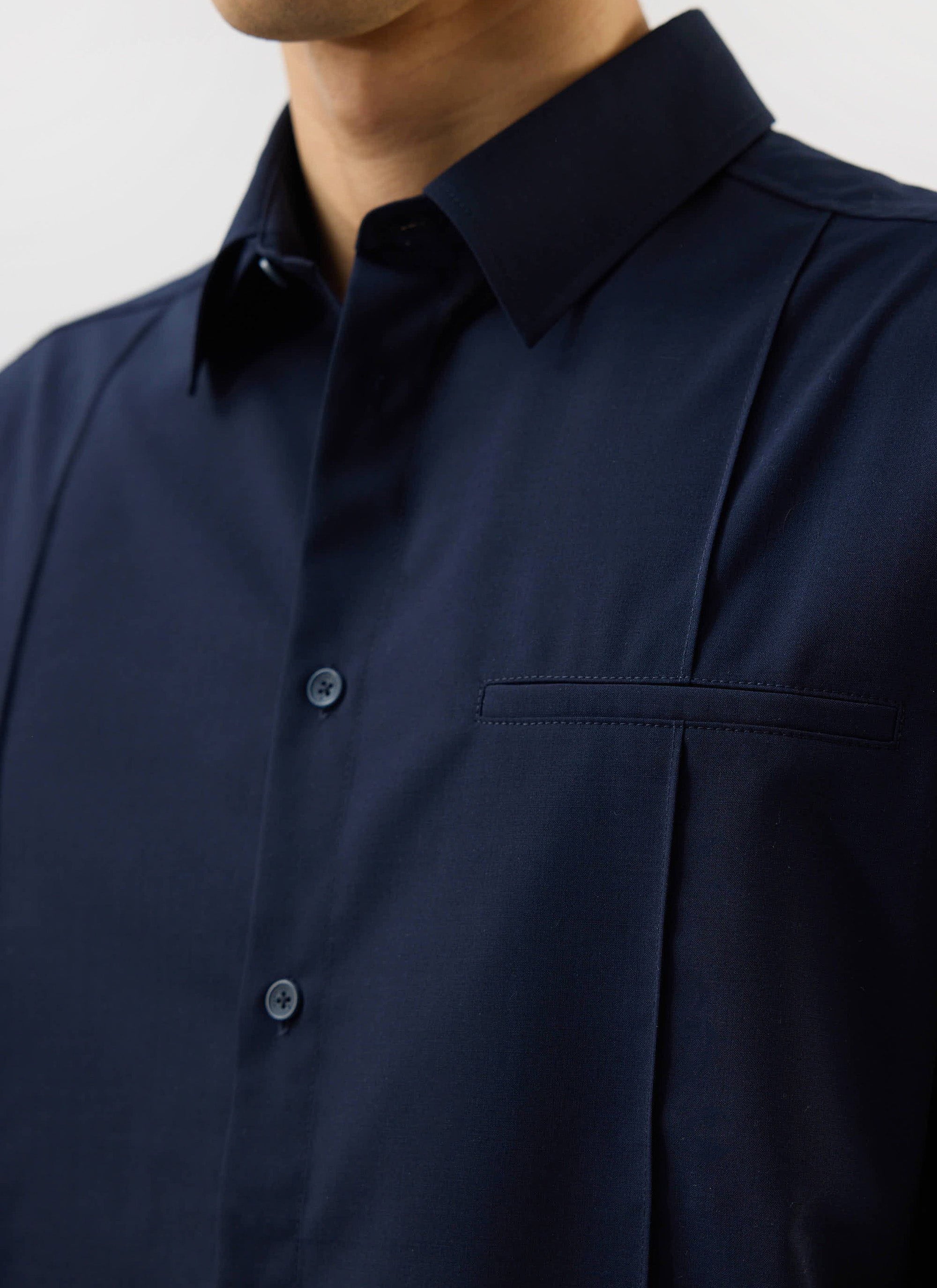 A close-up of the Percival x Warren Pleated Shirt in navy blue, showing the collar and unique vertical pleat detail.