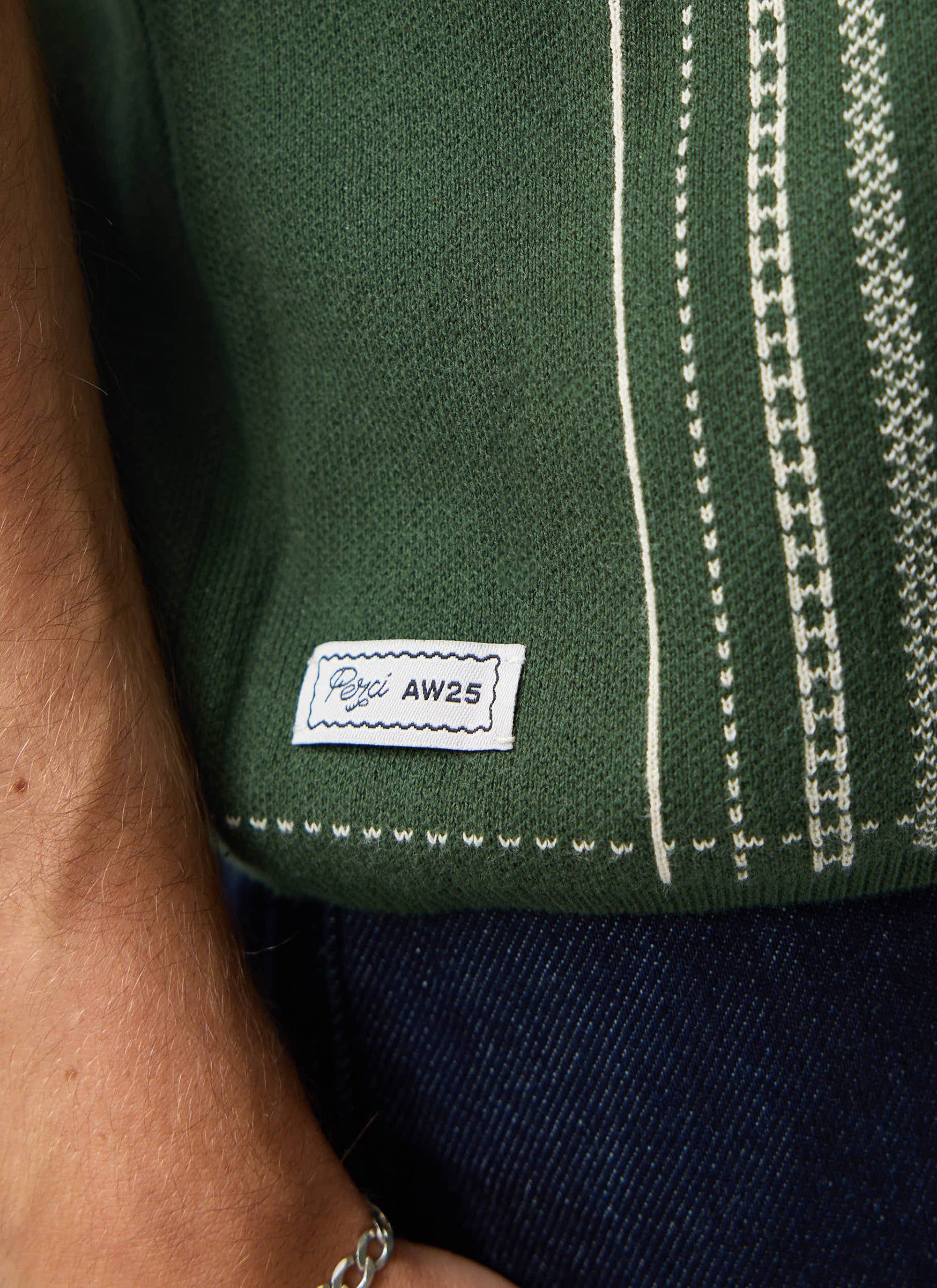 A close-up of the Percival Accolades Knitted Shirt in forest green, showing the white jacquard stitching and branded label.