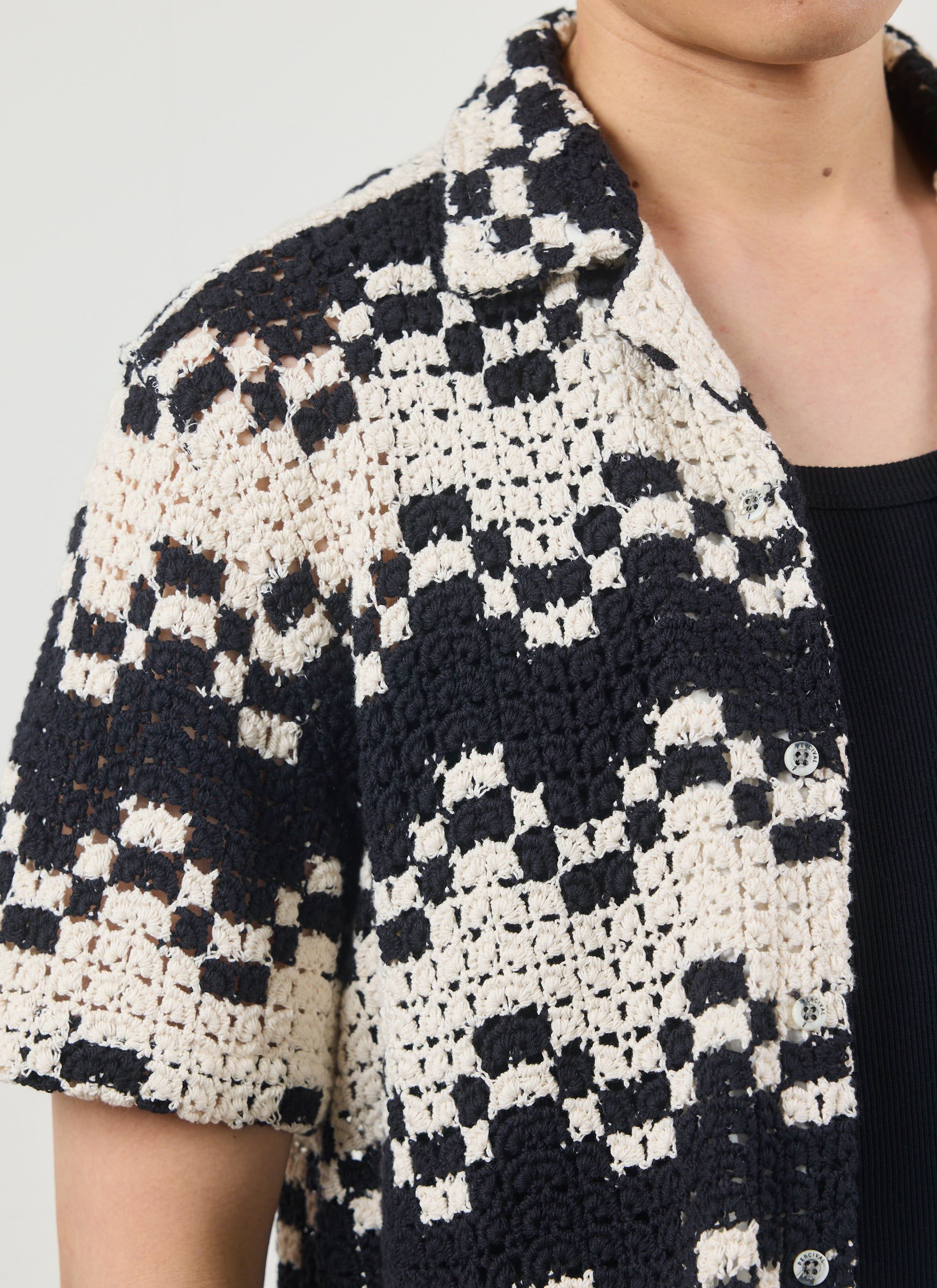 A close-up of a model wearing the Percival Naples Crochet Cuban Shirt, showing the black and ecru checked crochet detail.