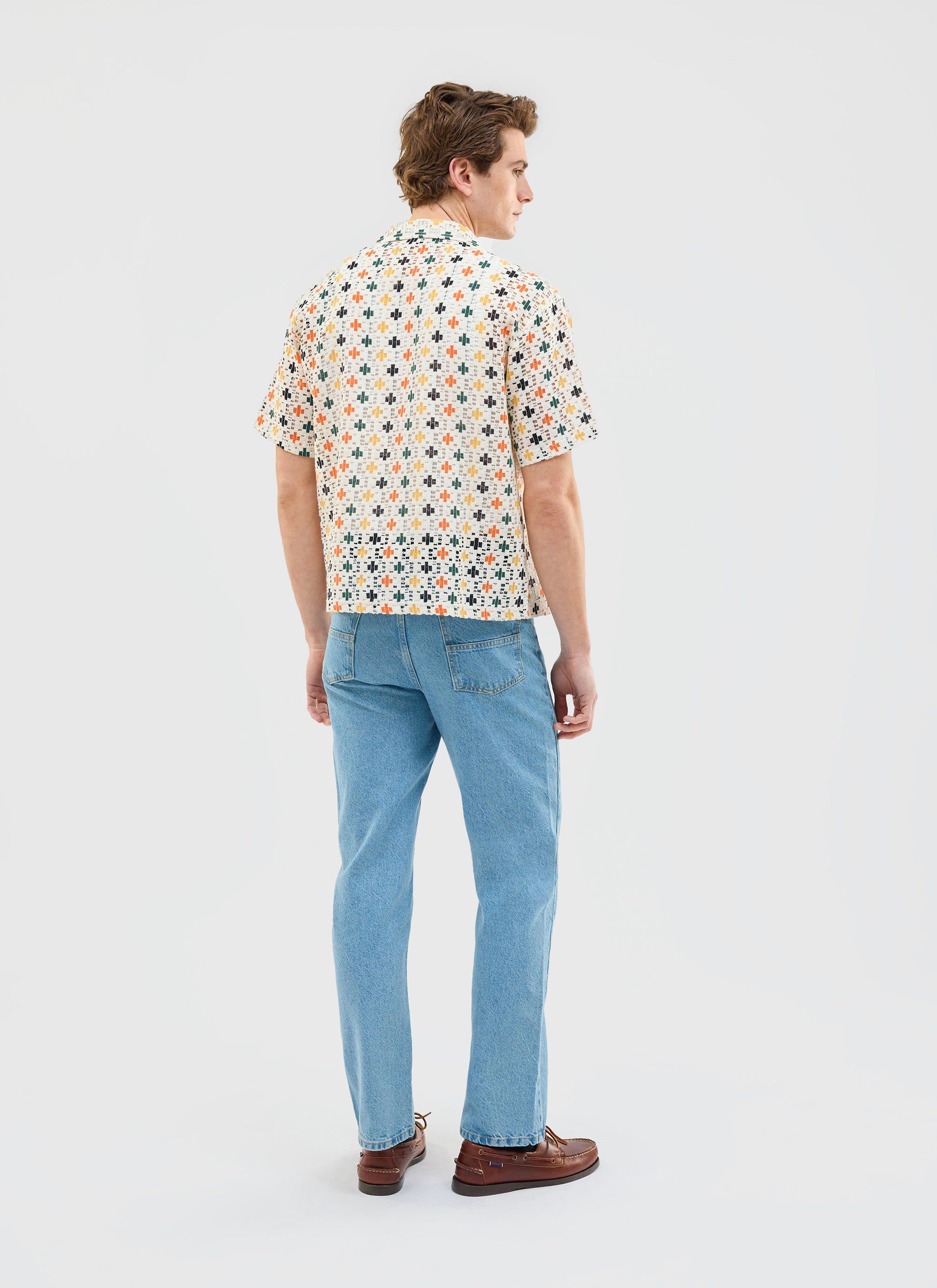 Back view of a model wearing the Percival Bailing Crochet Cuban Shirt in multi, paired with light wash jeans and boat shoes.