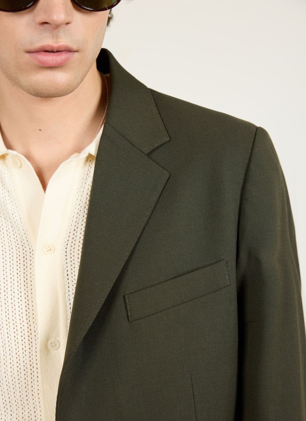 Close up of the Percival forest green wool tailored blazer, showing the lapel and pocket detail.