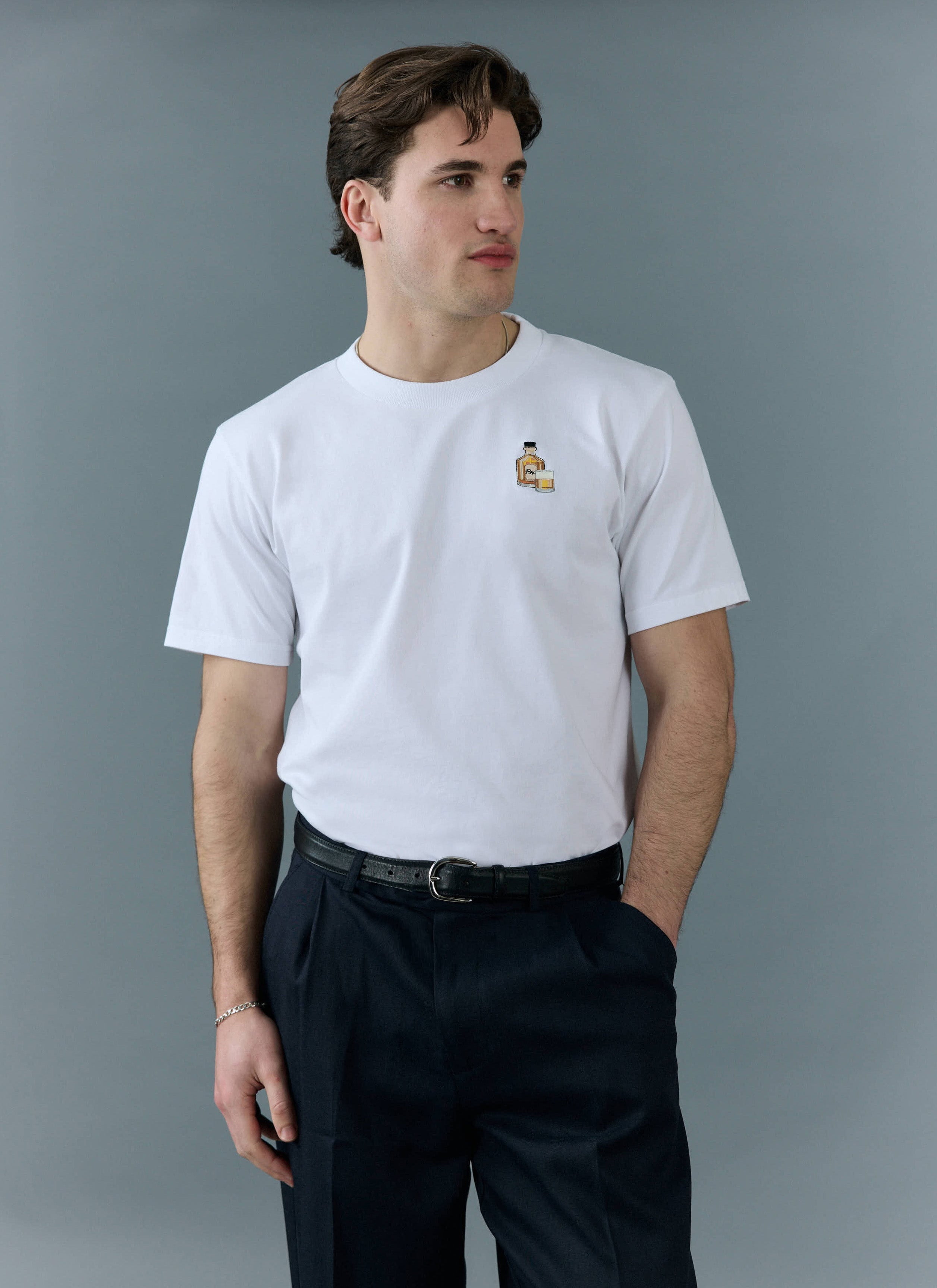 A man models the white Old Fashioned T Shirt from Percival, showing the detailed cocktail embroidery on the chest.