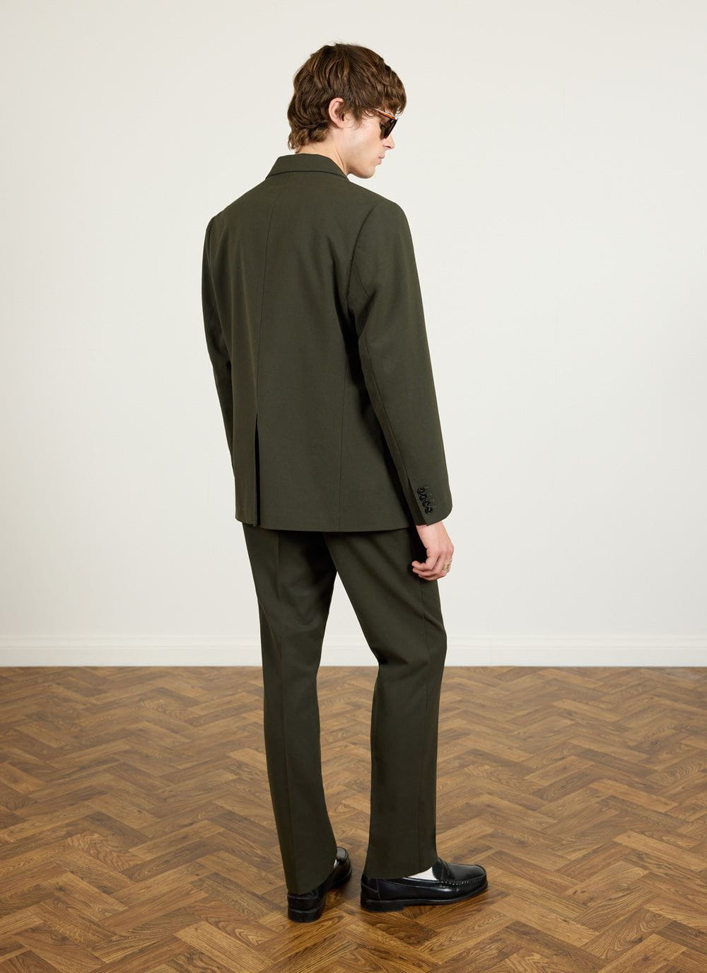 Back view of a man wearing the Percival forest green tailored wool blazer and matching trousers.