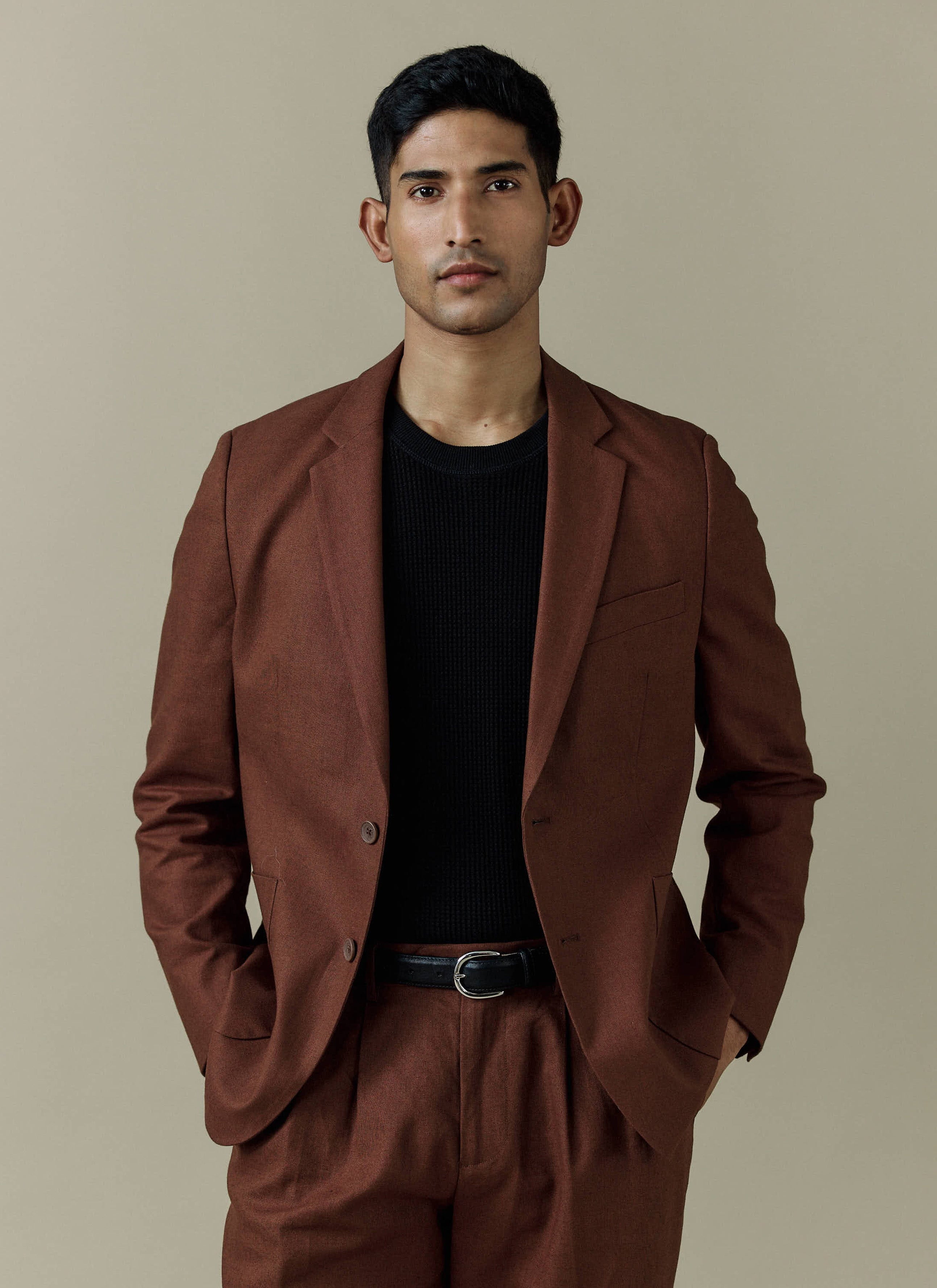 A model wears the Percival Tailored Linen Blazer in brown, styled with matching trousers and a black knit.