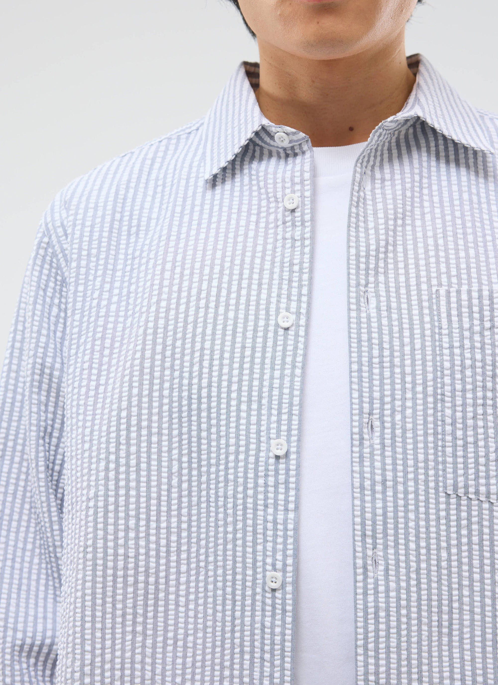 Close-up of a model wearing the Percival Seersucker Stripe Pearce Shirt in grey over a white t-shirt.