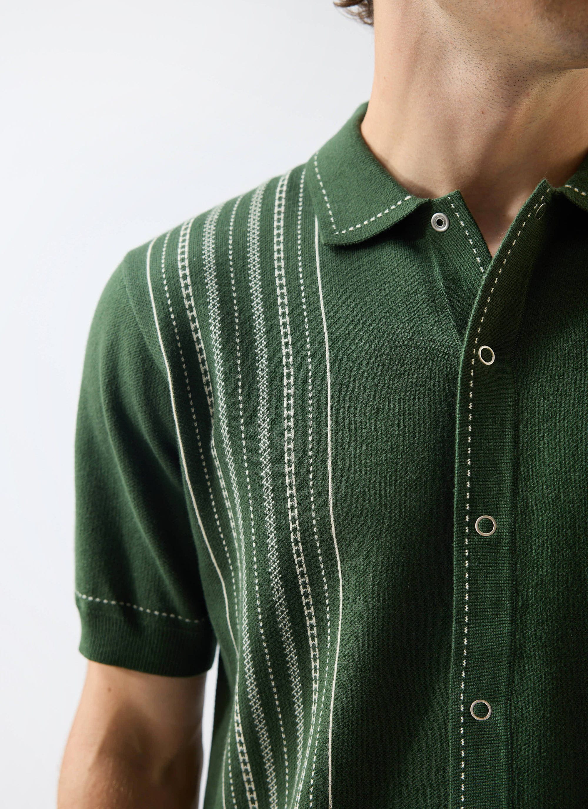 Close-up of a man wearing the Percival Accolades Knitted Shirt in forest green, showing the white jacquard stitch detailing.