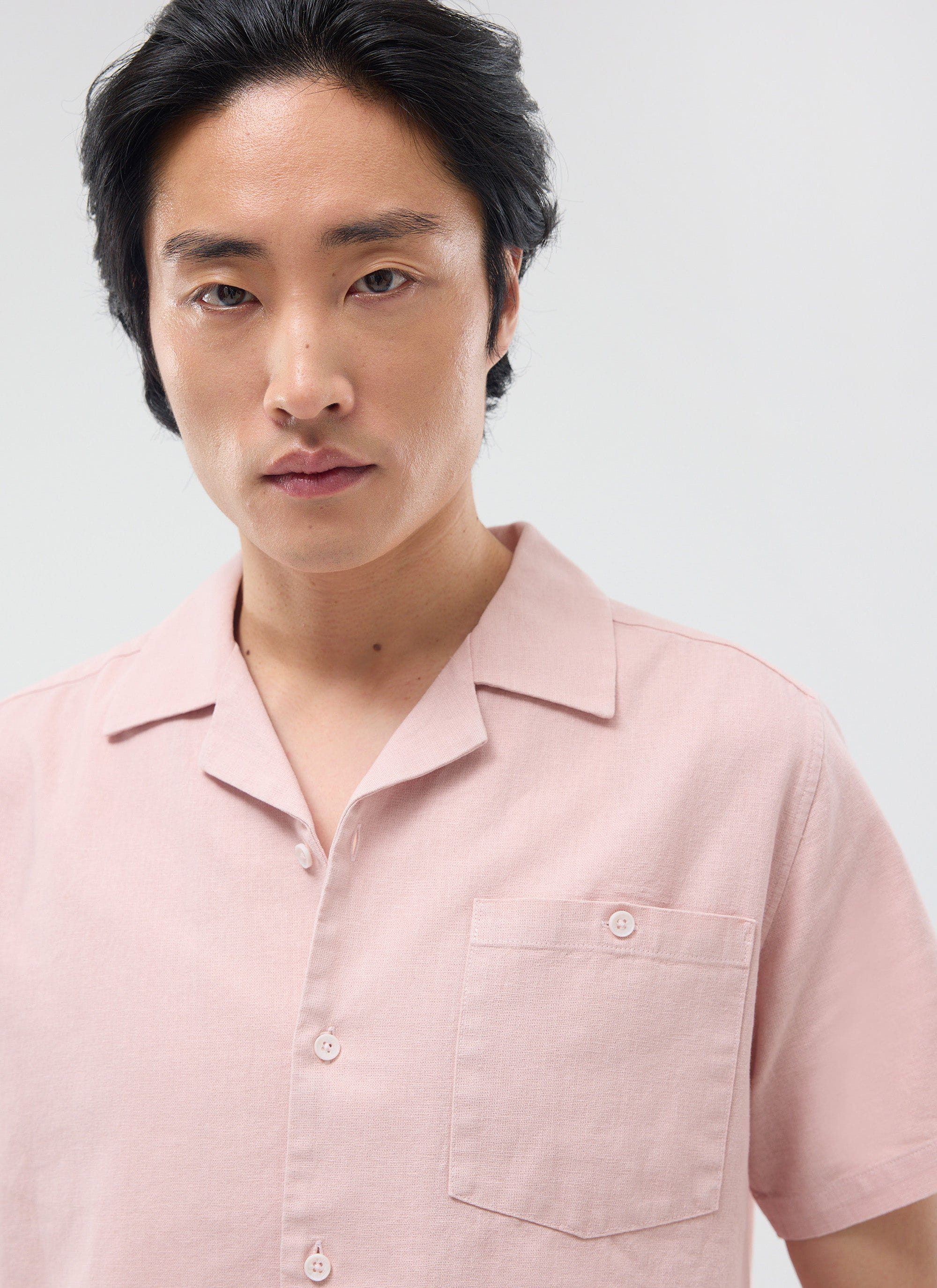 A close-up of a model wearing the Percival Short Sleeve Cuban Shirt, crafted from a dusty pink linen blend.
