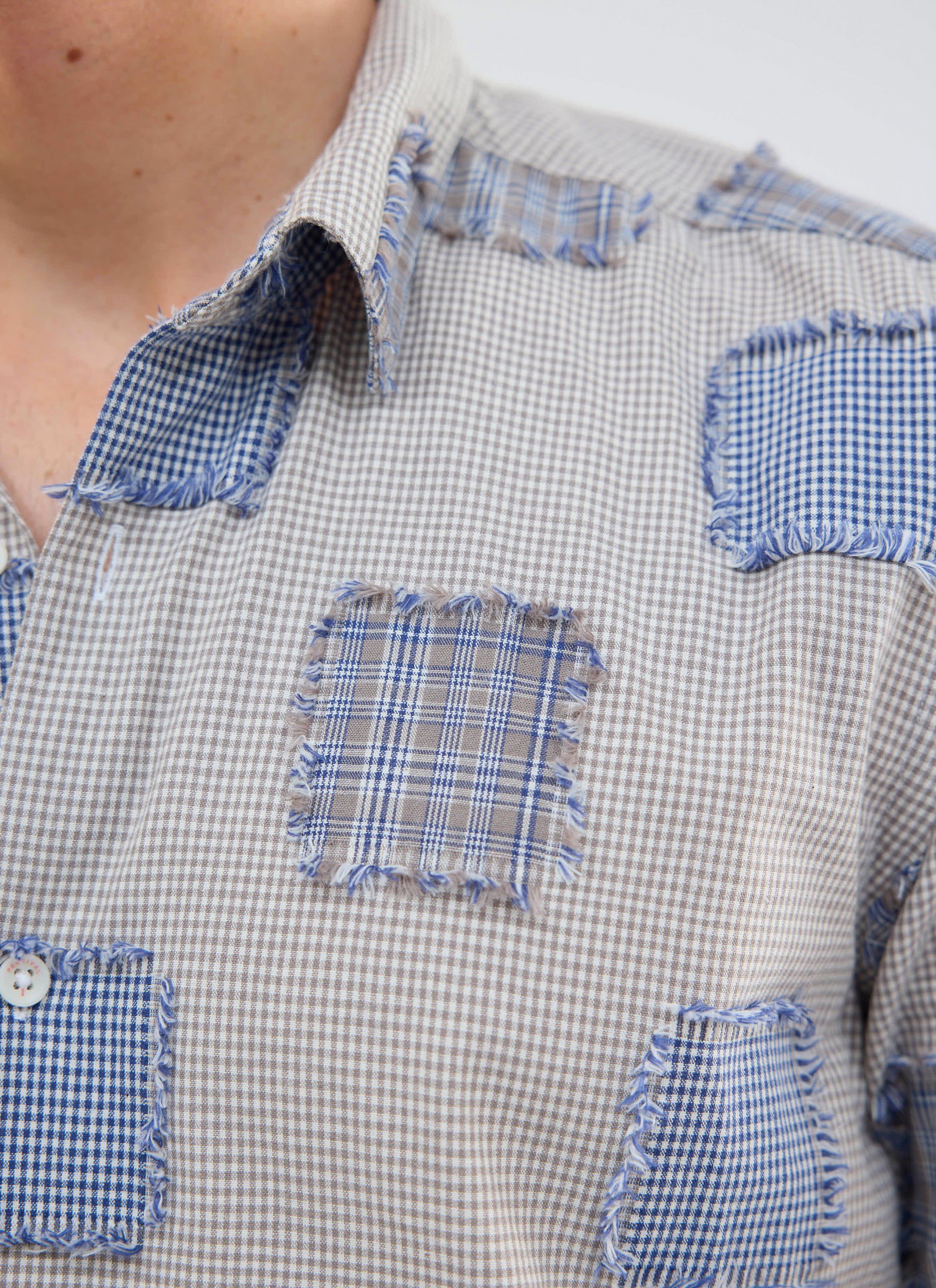 Close up of a model wearing the Percival Bruno Boxy Clerk Shirt in grey, showing the frayed flannel patchwork detail.