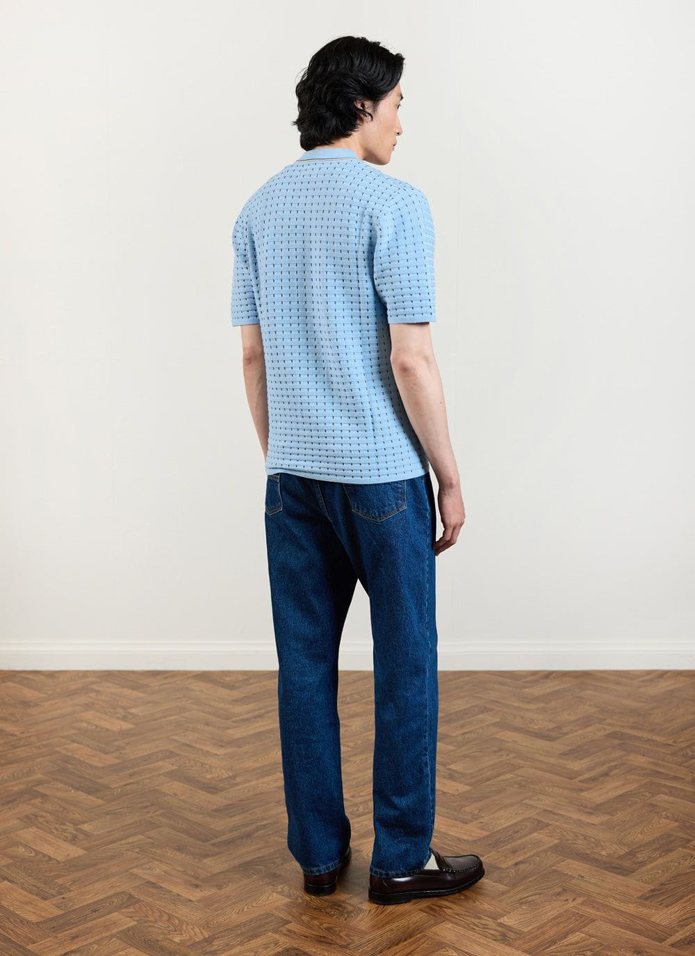 Model seen from behind wearing the Percival blue Broken Stripe Knitted Shirt with dark wash jeans.