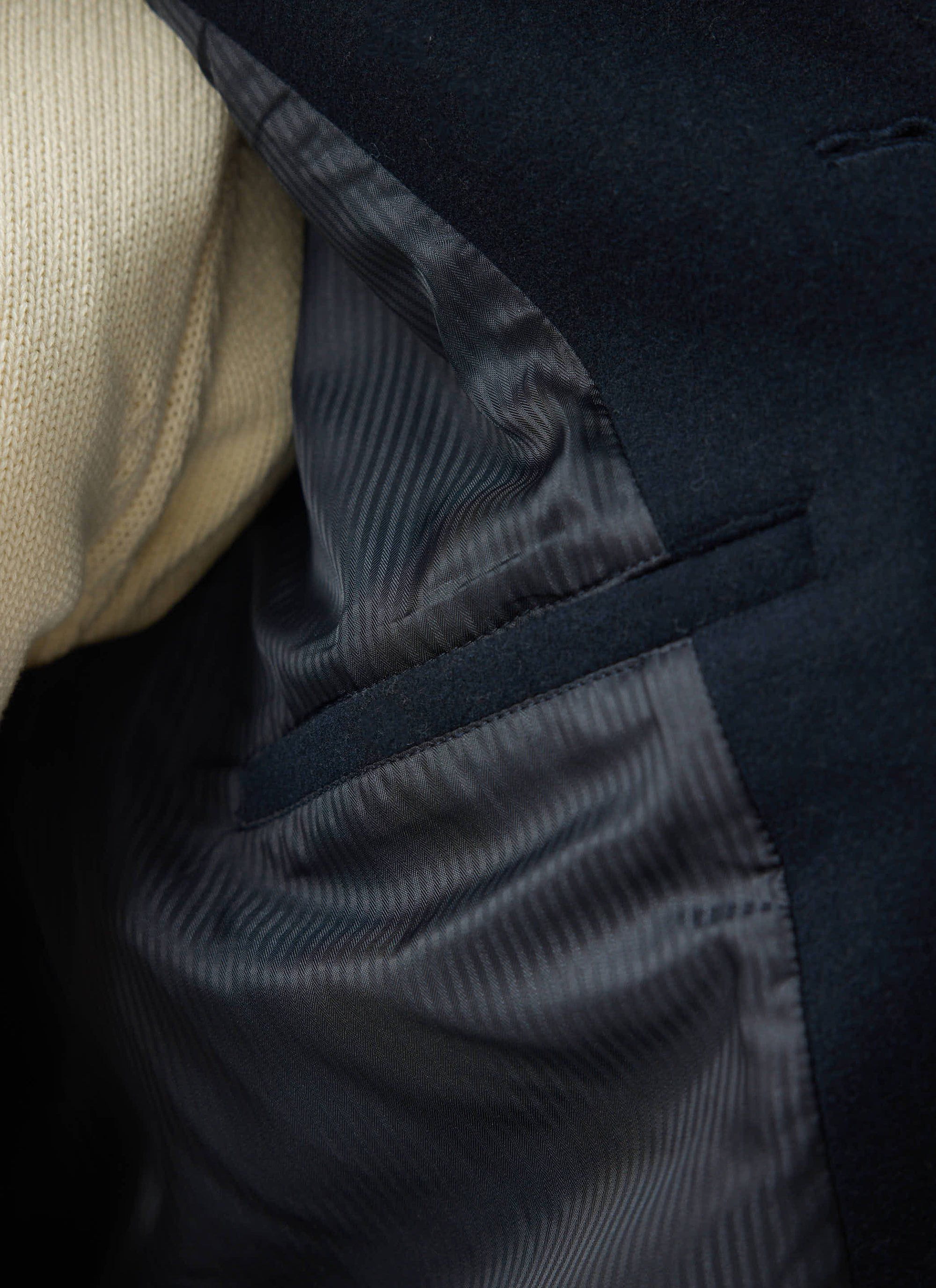 A close-up shot of the Percival Navy Peacoat, revealing the tonal jacquard lining and internal welt pocket.