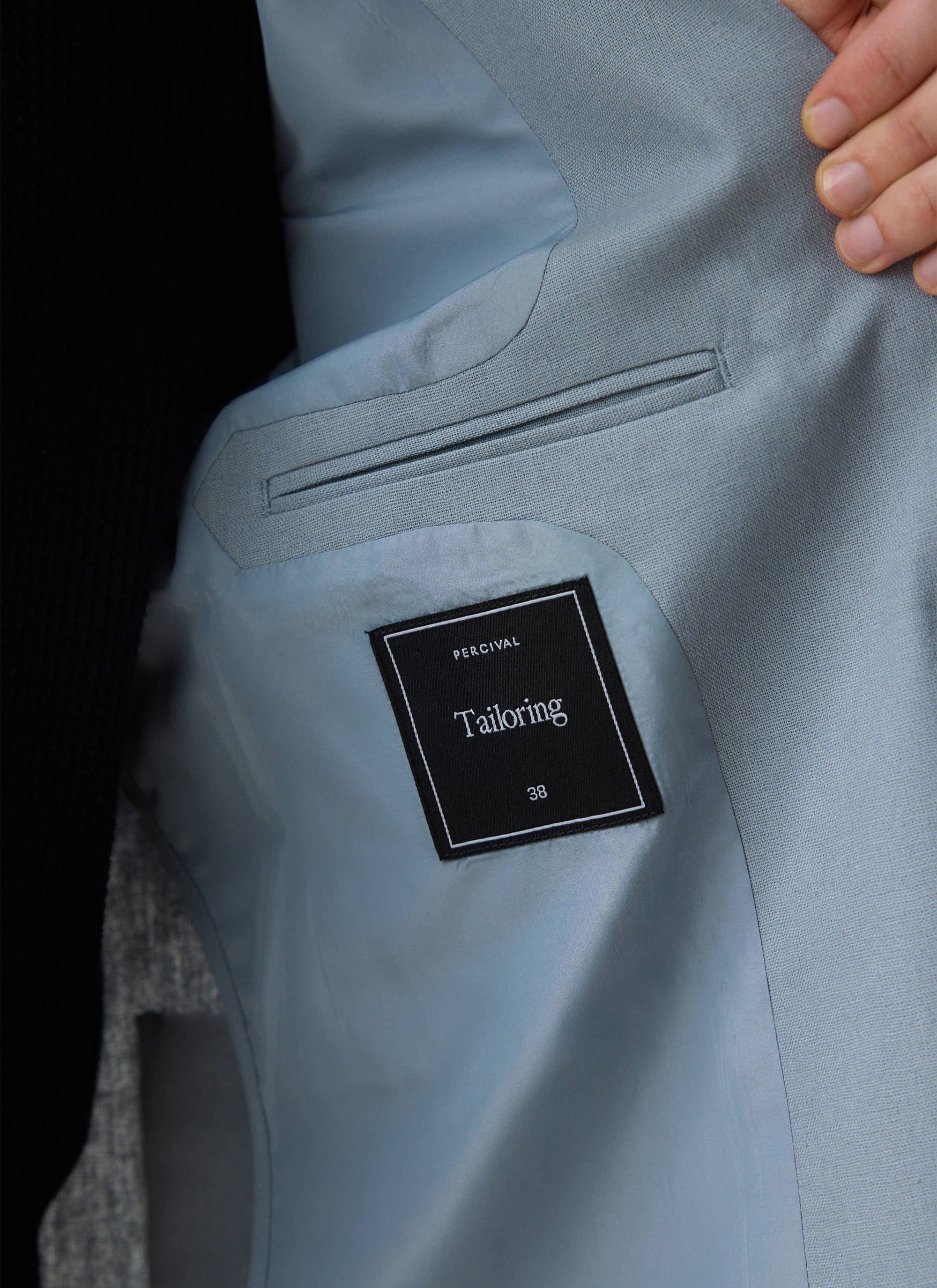 Close up of the light blue Percival tailored linen blazer, showing the internal pocket and branding label.