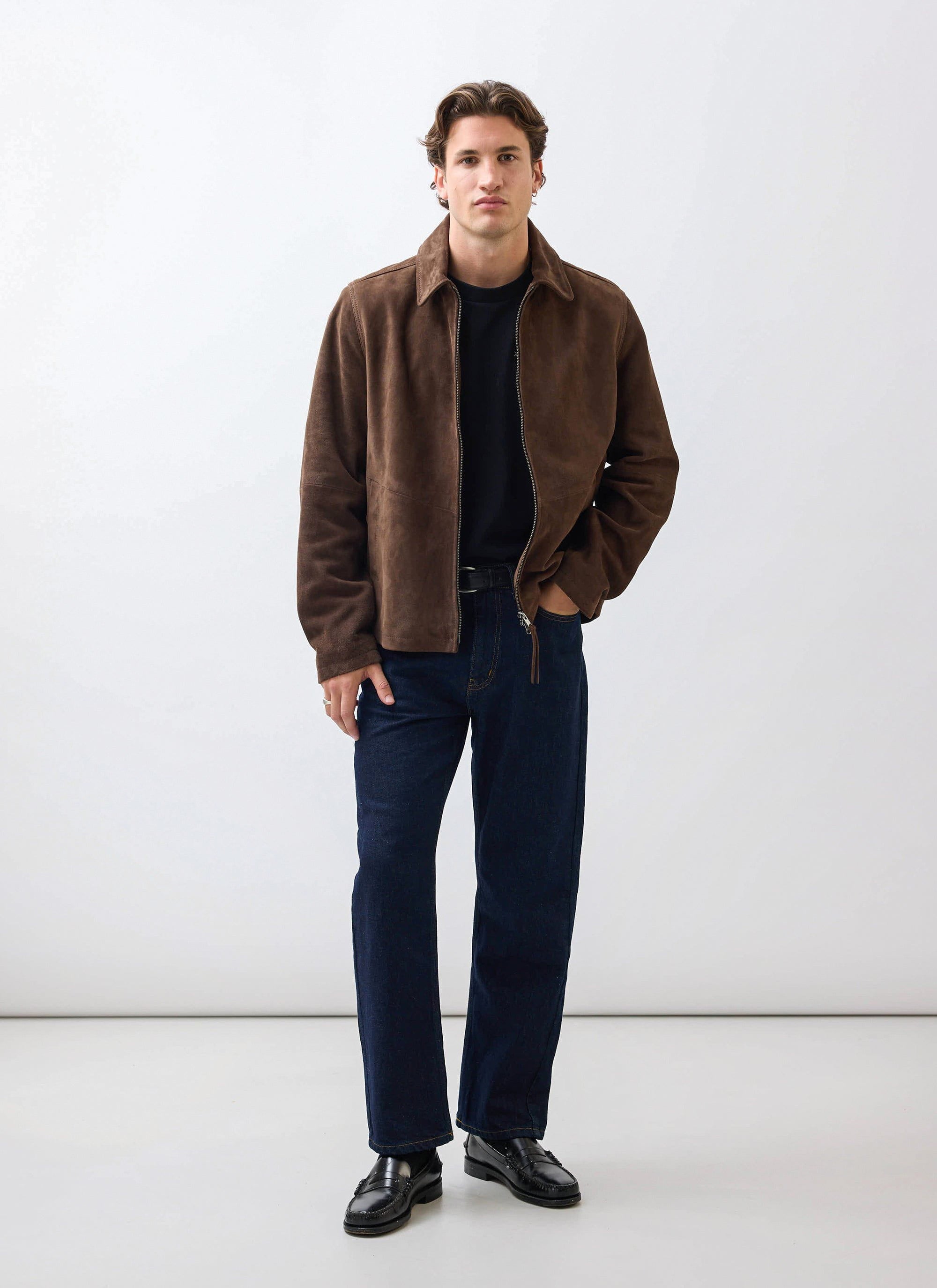 A male model wearing the Percival Prologue Soft Suede Jacket in espresso brown with dark jeans and black loafers.