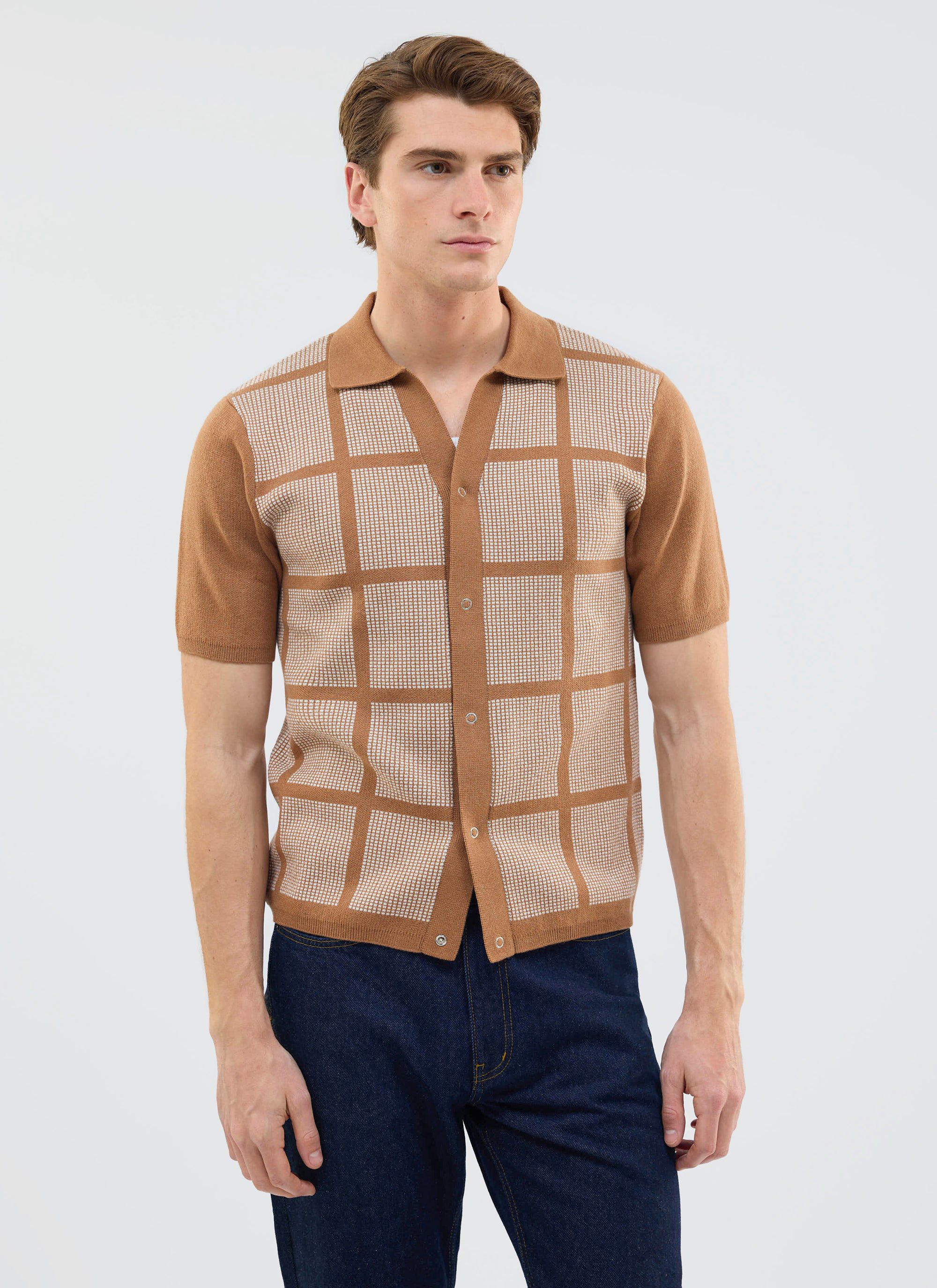A model wears the Percival Costa Knitted Shirt in tobacco, a retro-style top with a square design, styled with dark jeans.