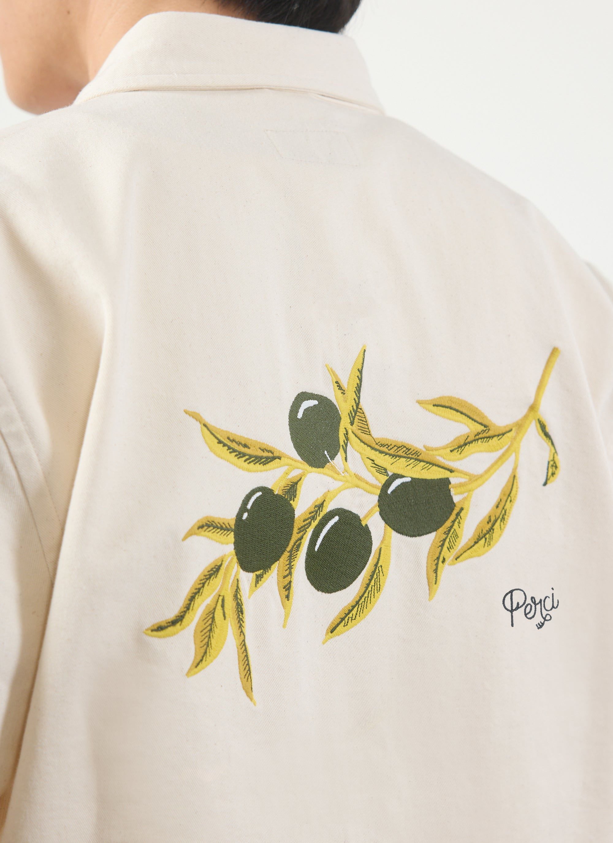 A close-up of the olive branch embroidery on the back of the white cropped cotton shirt by Percival.