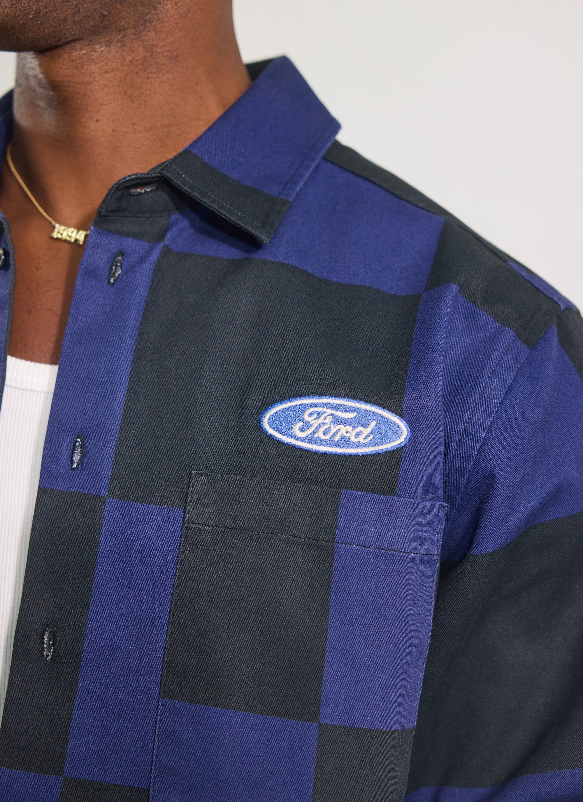 Close-up of the Percival x Ford navy and black checkerboard overshirt, featuring the embroidered Ford logo on the chest.