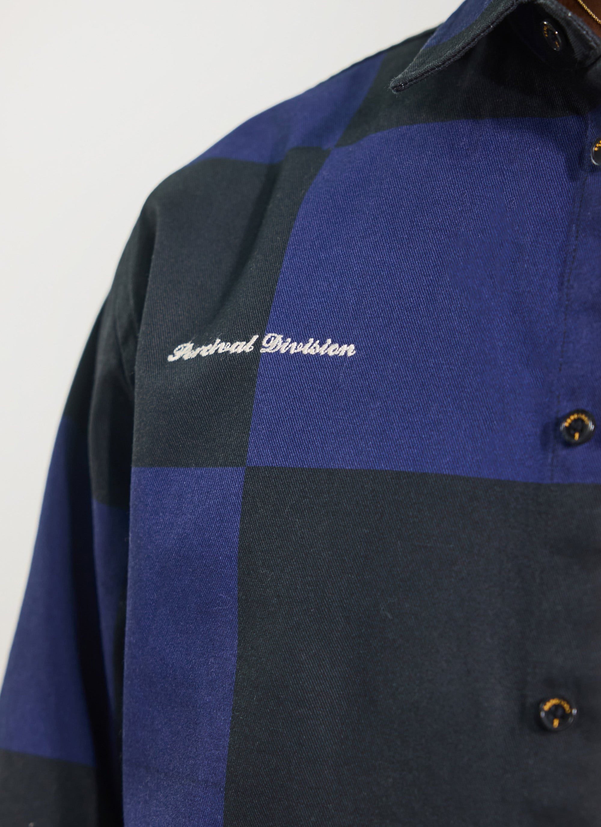 Close up of the Percival x Ford navy and black checkerboard overshirt with 'Percival Division' embroidery.