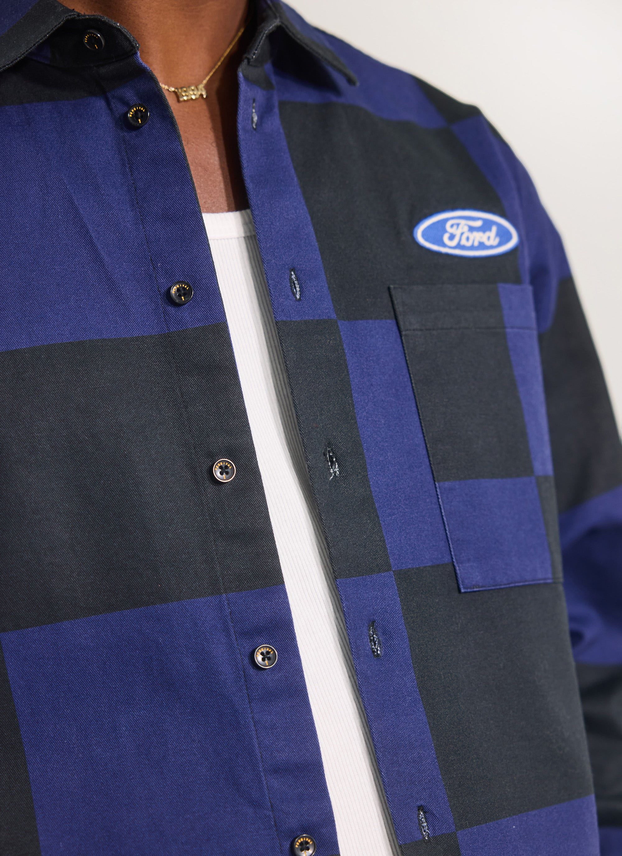 Close up of the Percival x Ford navy and black checkerboard overshirt showing the Ford chest logo and branded buttons.