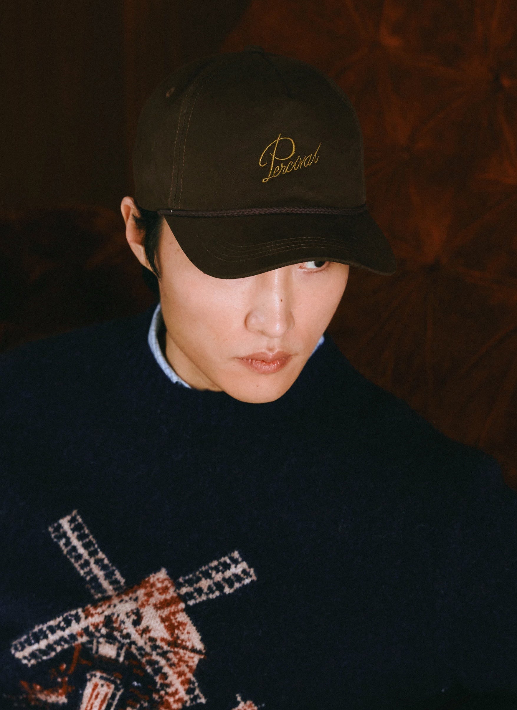 A model wearing the charcoal Percival Luther soft trucker cap in brushed cotton with embroidered script.