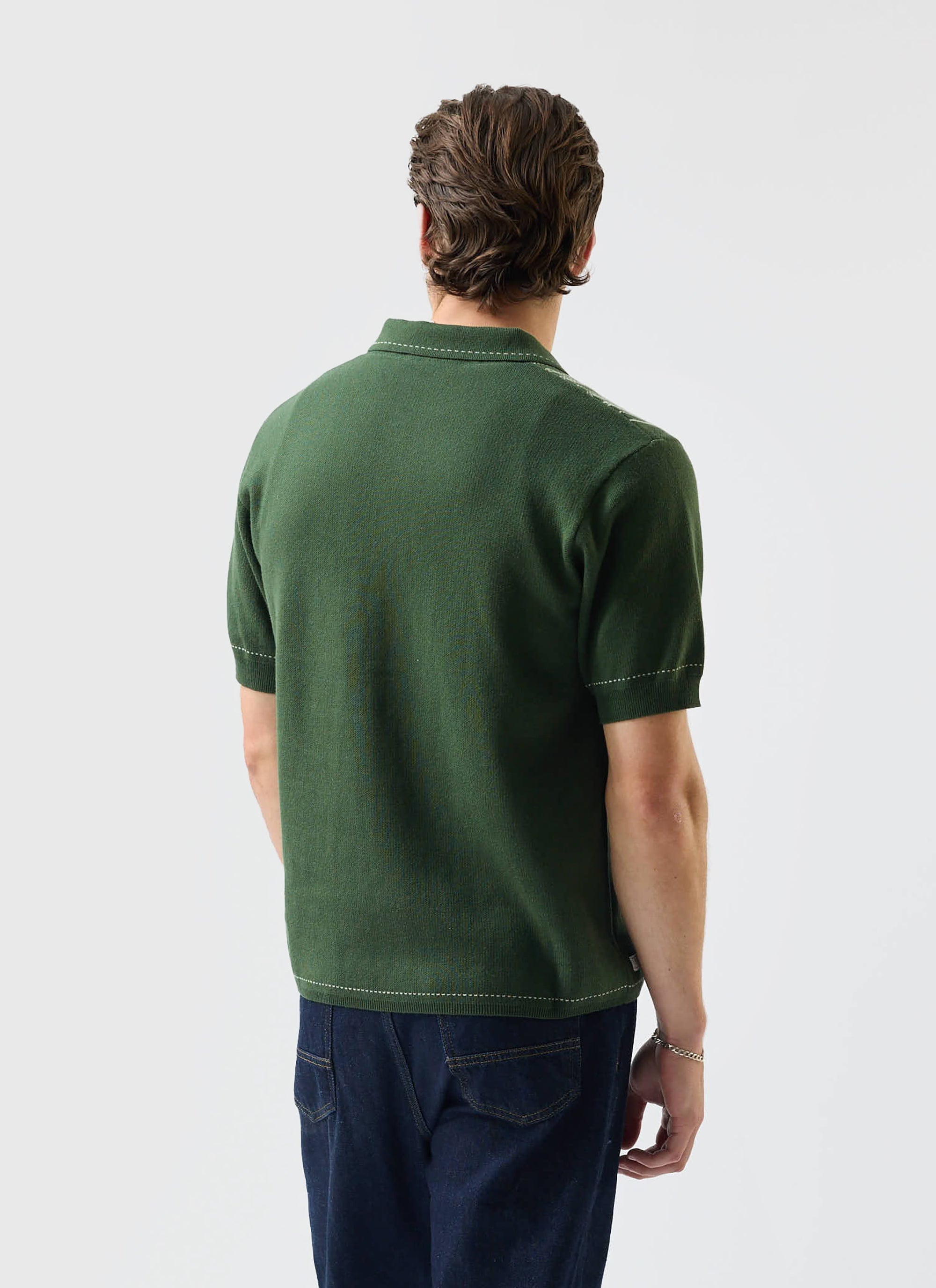 Back view of a model wearing the Percival Accolades Knitted Shirt in forest green, showing the contrast stitch detail.