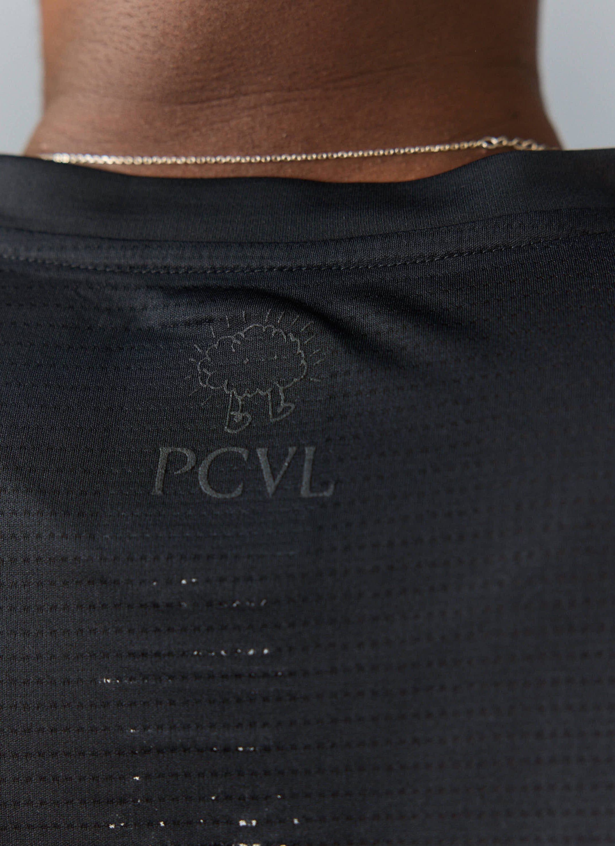 Detail shot of the tonal black PCVL logo on the ventilated mesh back of the black Performance T-Shirt from Percival.